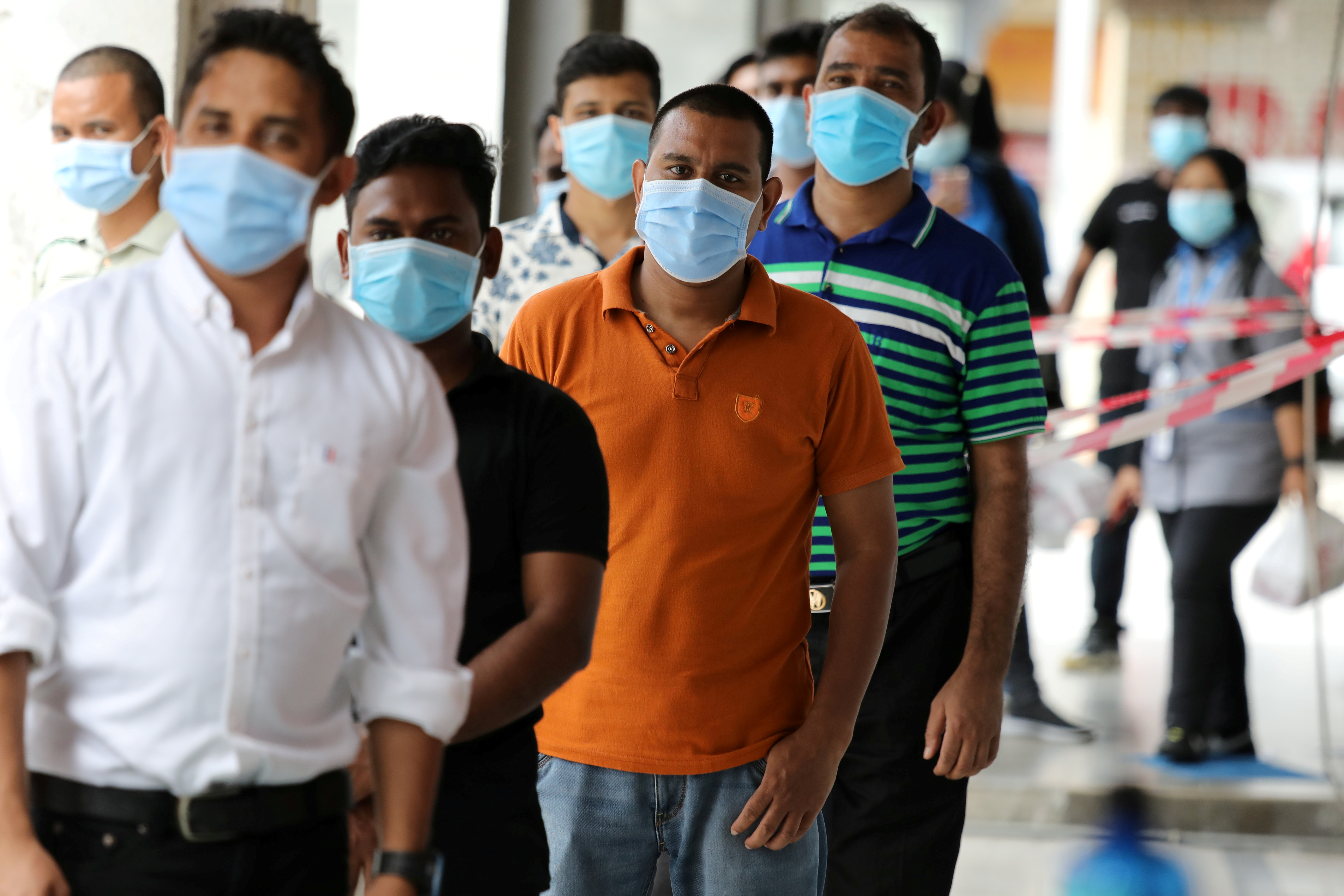 Foreign workers wait in line to be tested for the coronavirus disease (COVID-19) outside a clinic in Kajang