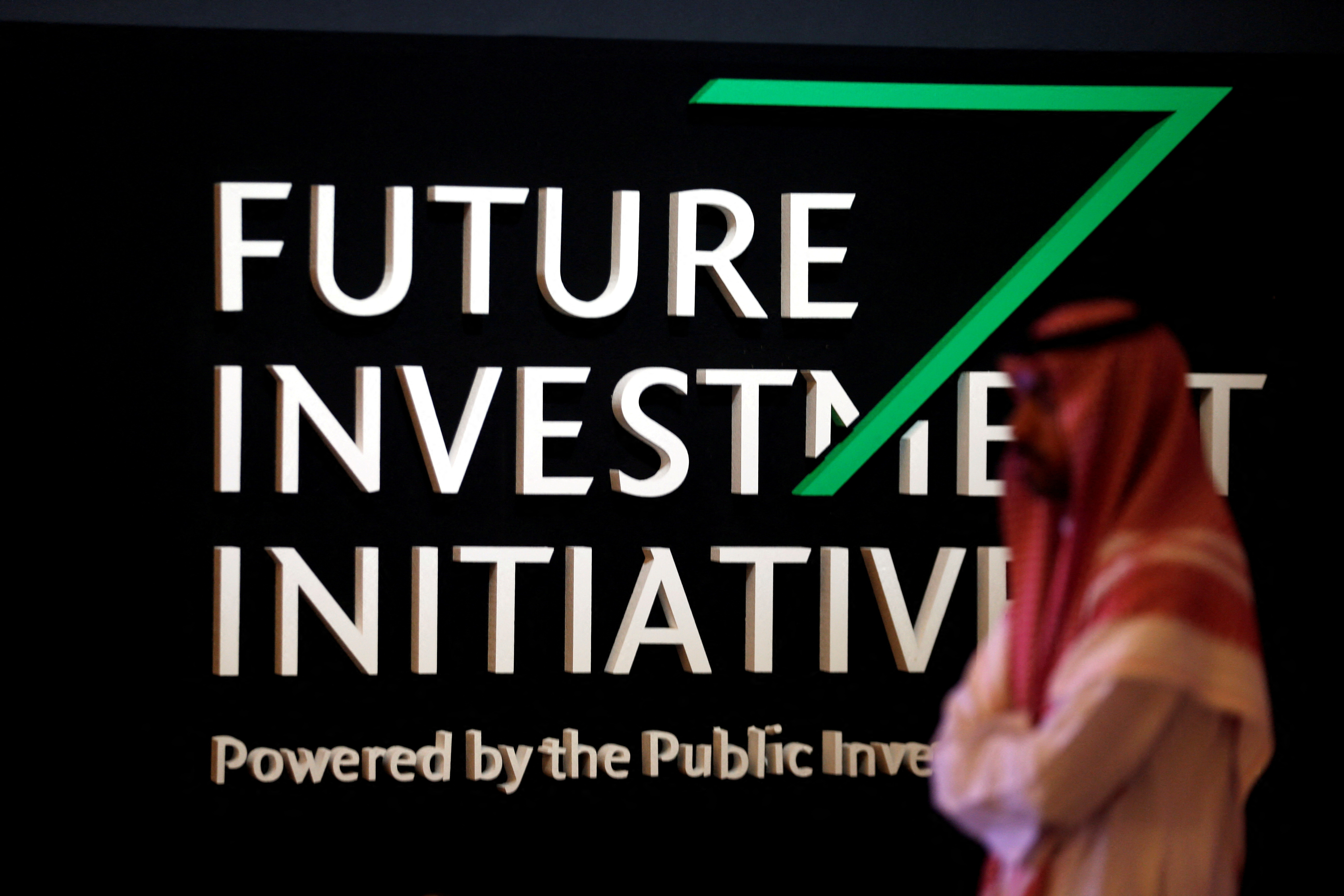 A Saudi man walks past the sign of the Future Investment Initiative during the last day of the investment conference in Riyadh