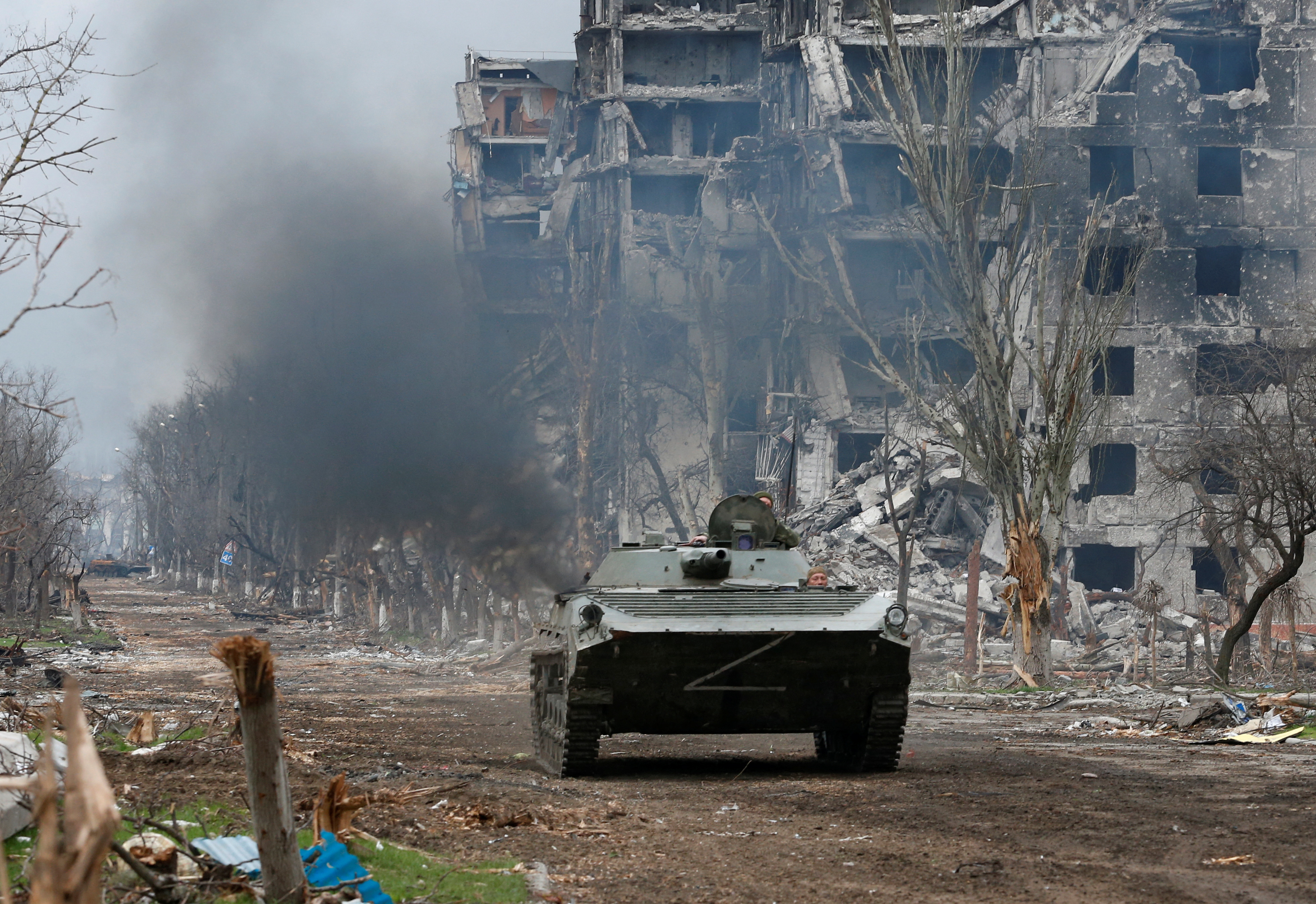Service members of pro-Russian troops ride an armoured vehicle during fighting near Azovstal plant in Mariupol
