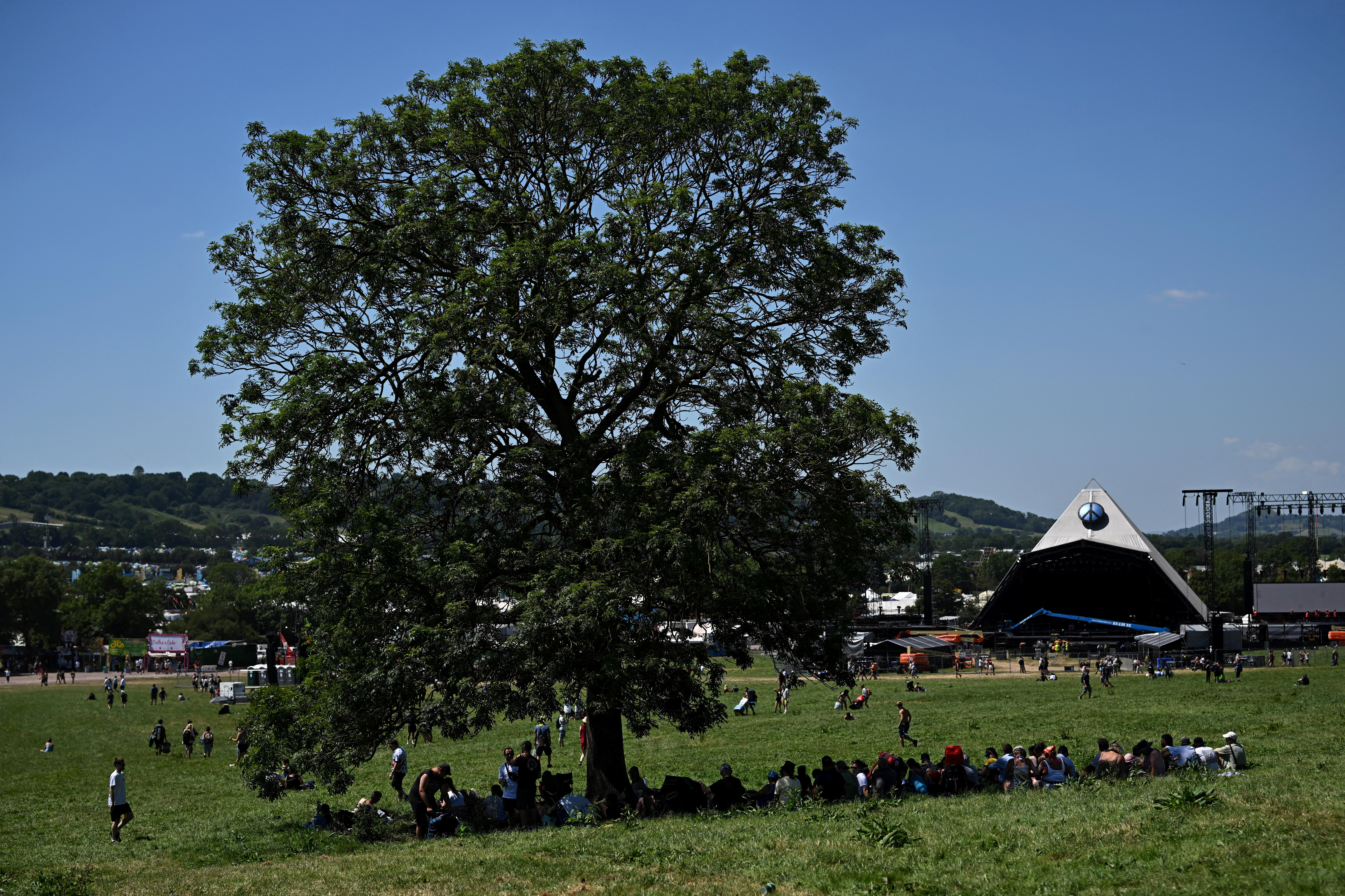 Revellers shade under a tree at Worthy Farm in Somerset during the Glastonbury Festival