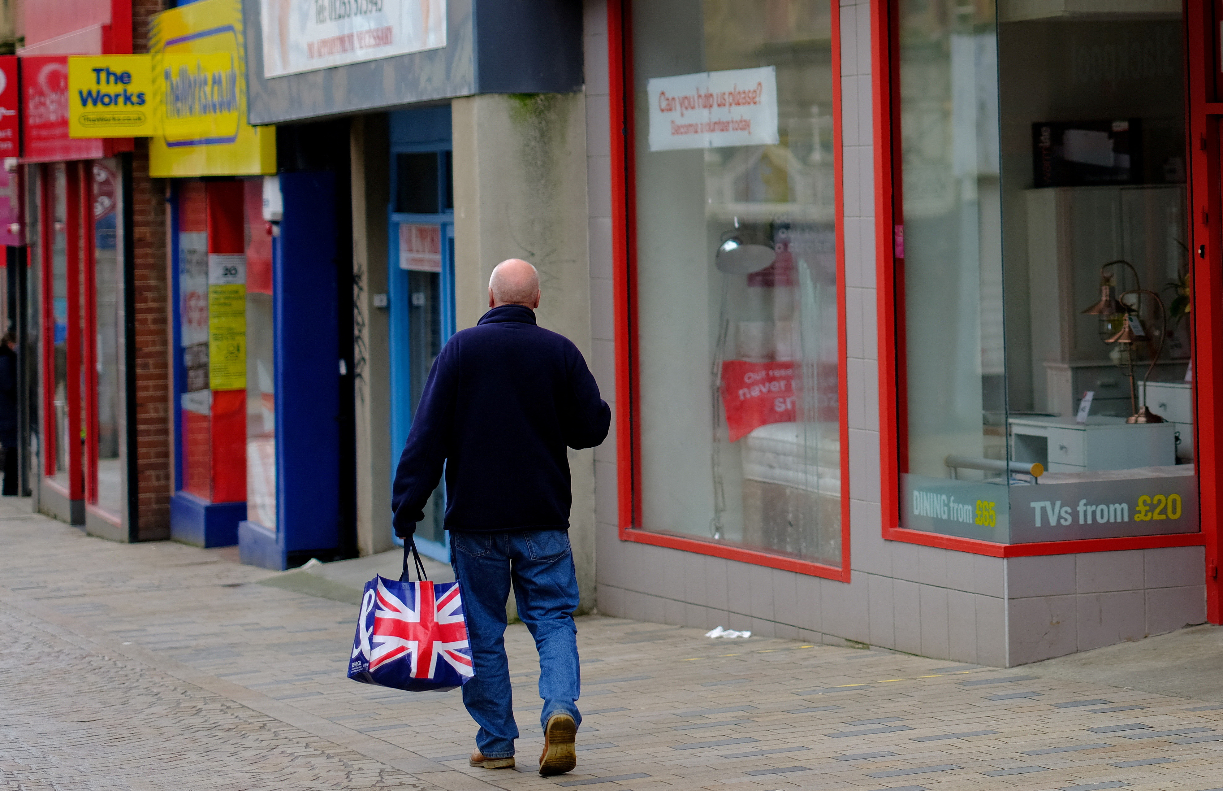 A man carries a Union Jack themed shopping bag as he walks along an empty shopping street in Blackpool