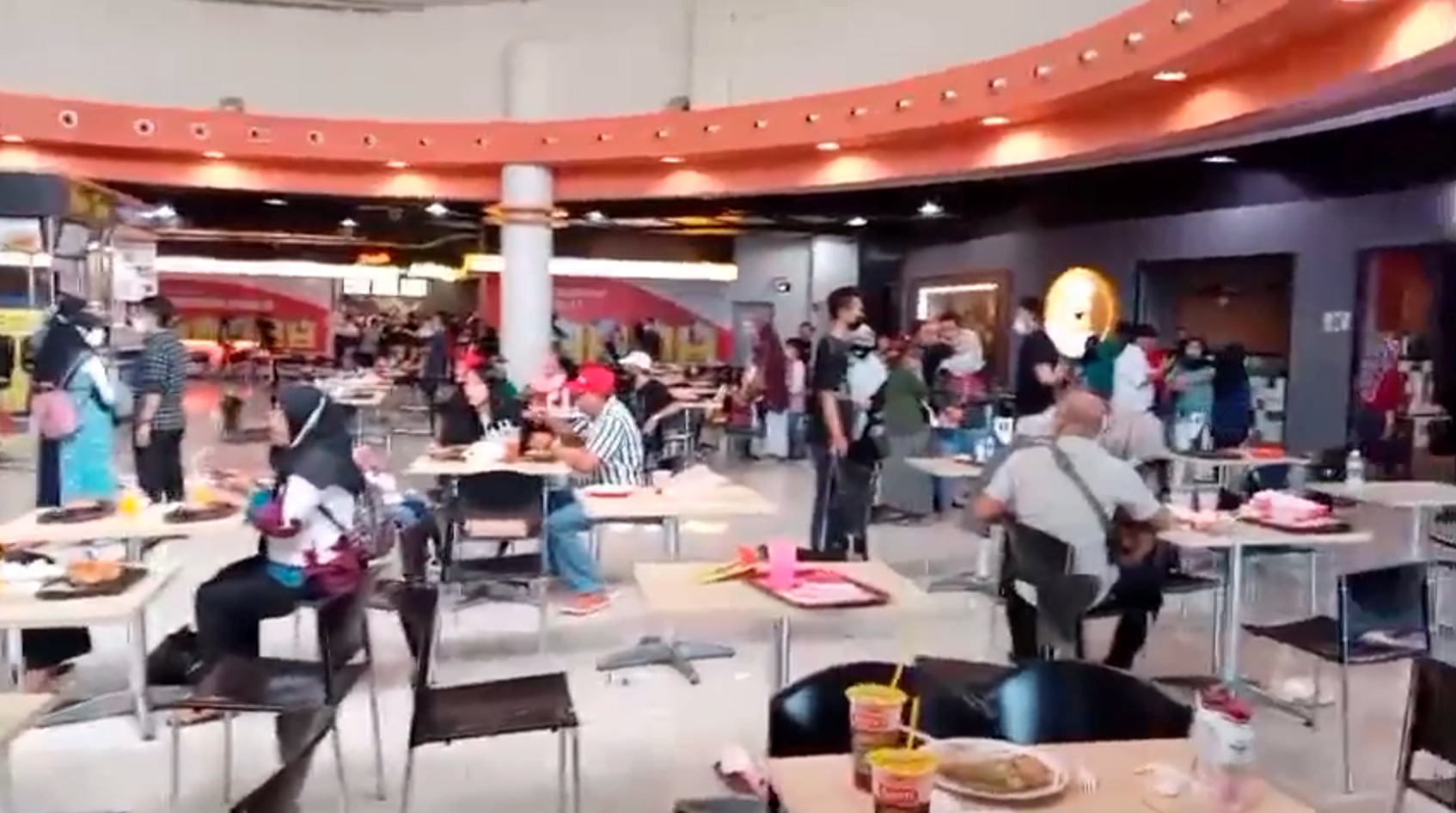 People stand during a tremor, at a food court in Royal Plaza in Surabaya