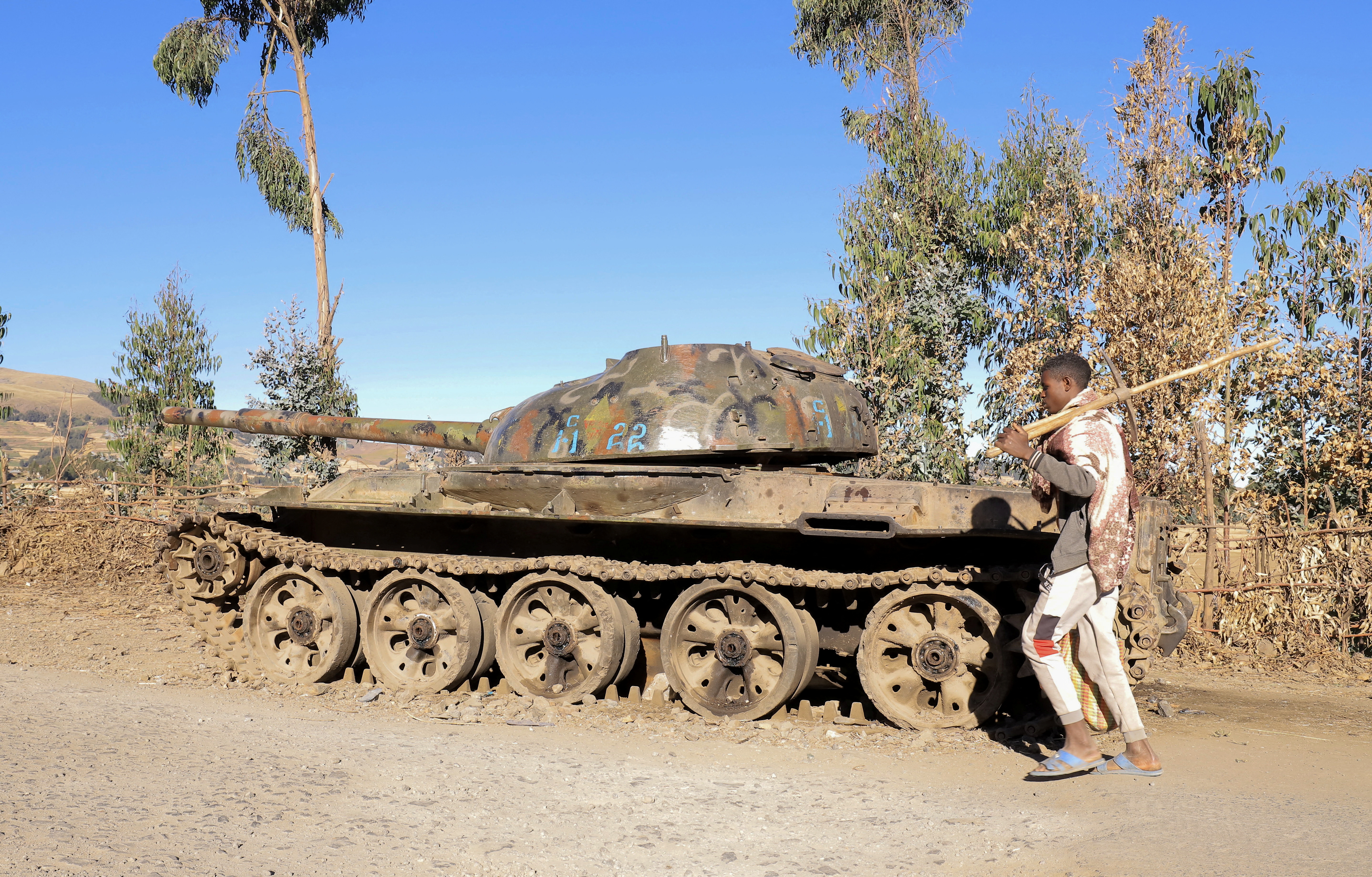 A  farmer walks past a military tank destroyed recently during fighting between the Ethiopian National Defense Force (ENDF) and the Tigray People's Liberation Front (TPLF) in Damot Kebele of Amhara region, Ethiopia December 7, 2021.  REUTERS/Kumera Gemechu  