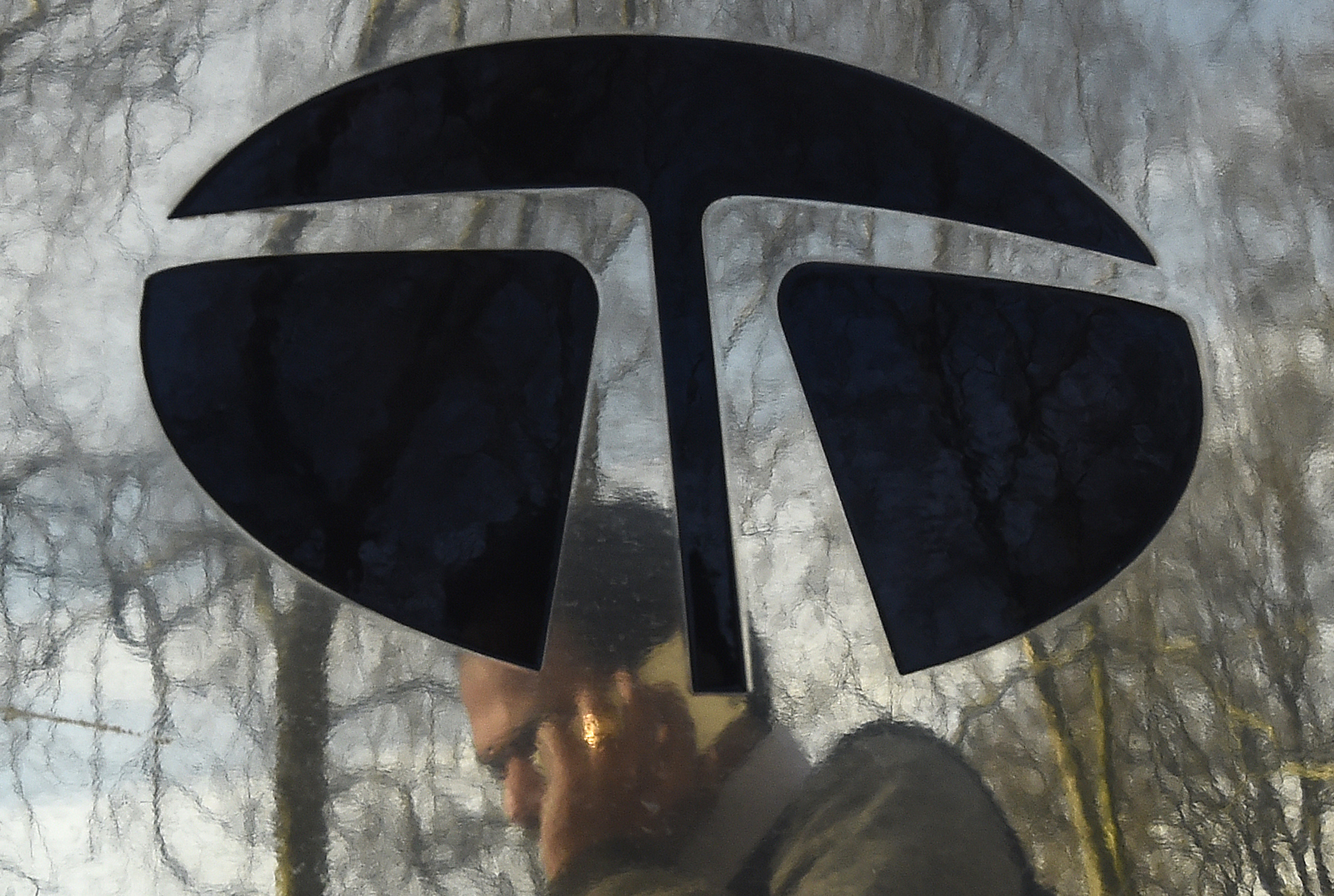 A man walks past a Tata sign outside their offices in London