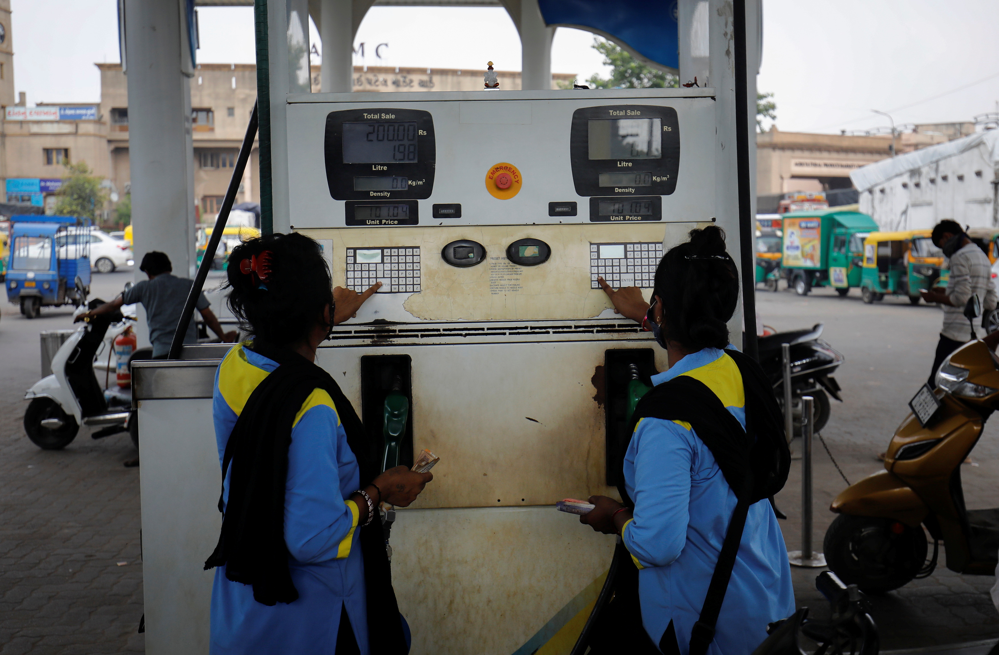 Workers pump fuel at a petrol station in Ahmedabad