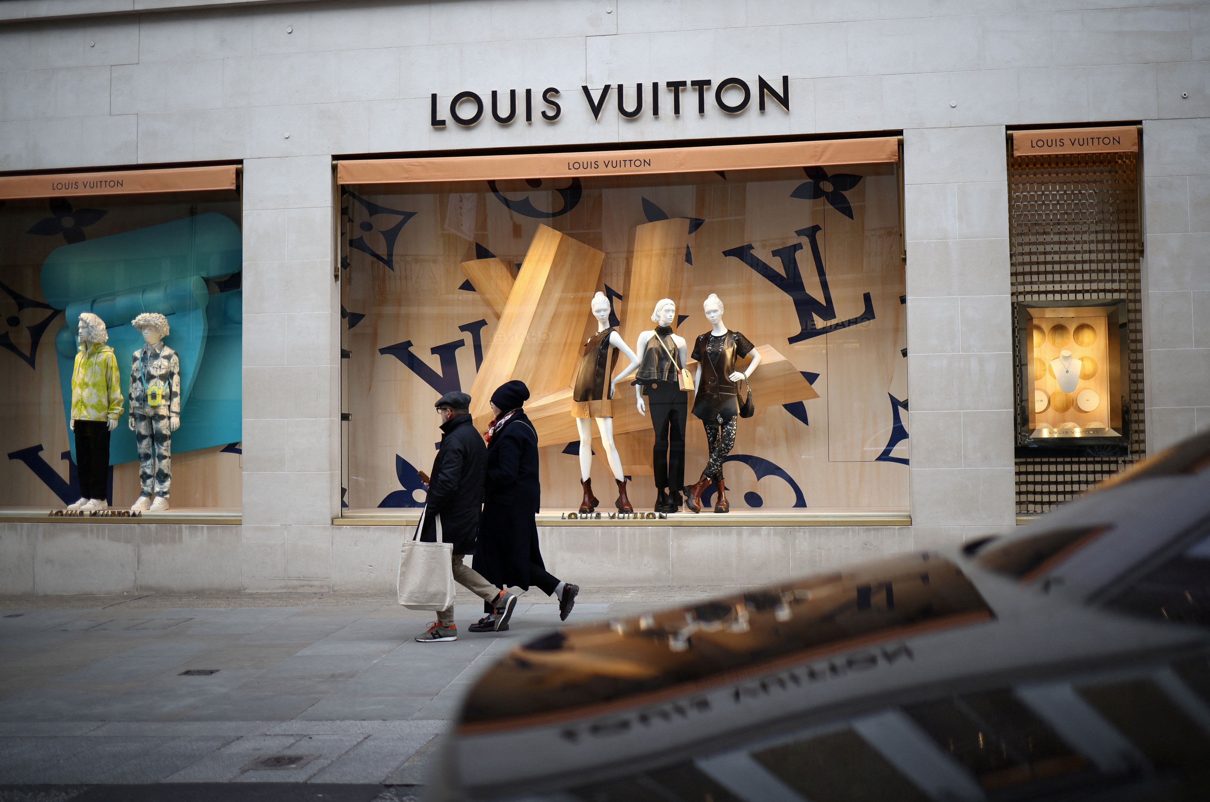 People walk outside a Louis Vuitton store on New Bond Street in London