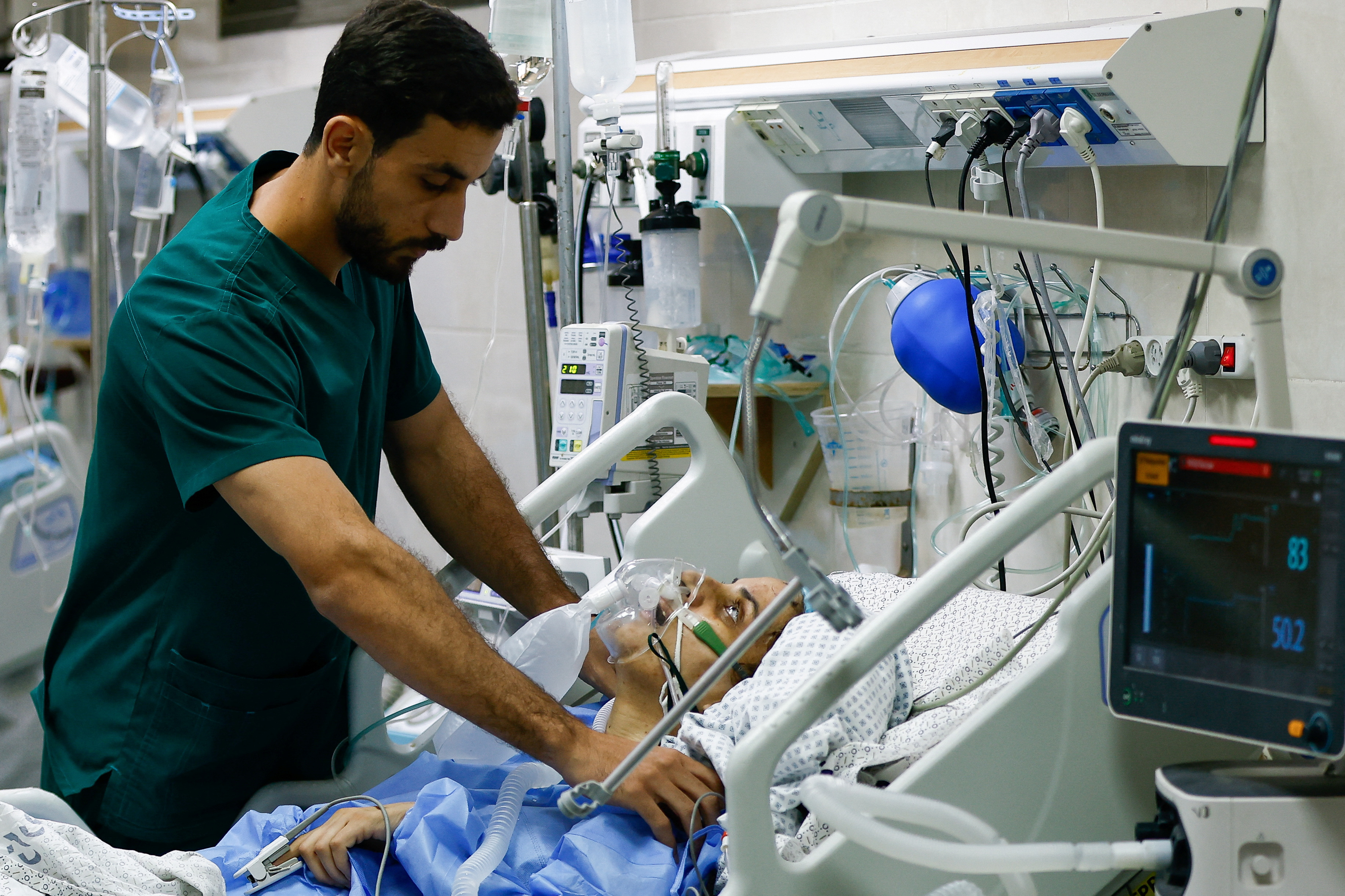 A medical worker assists a Palestinian, who was wounded in Israeli strikes, at the Intensive Care Unit (ICU) of Nasser hospital