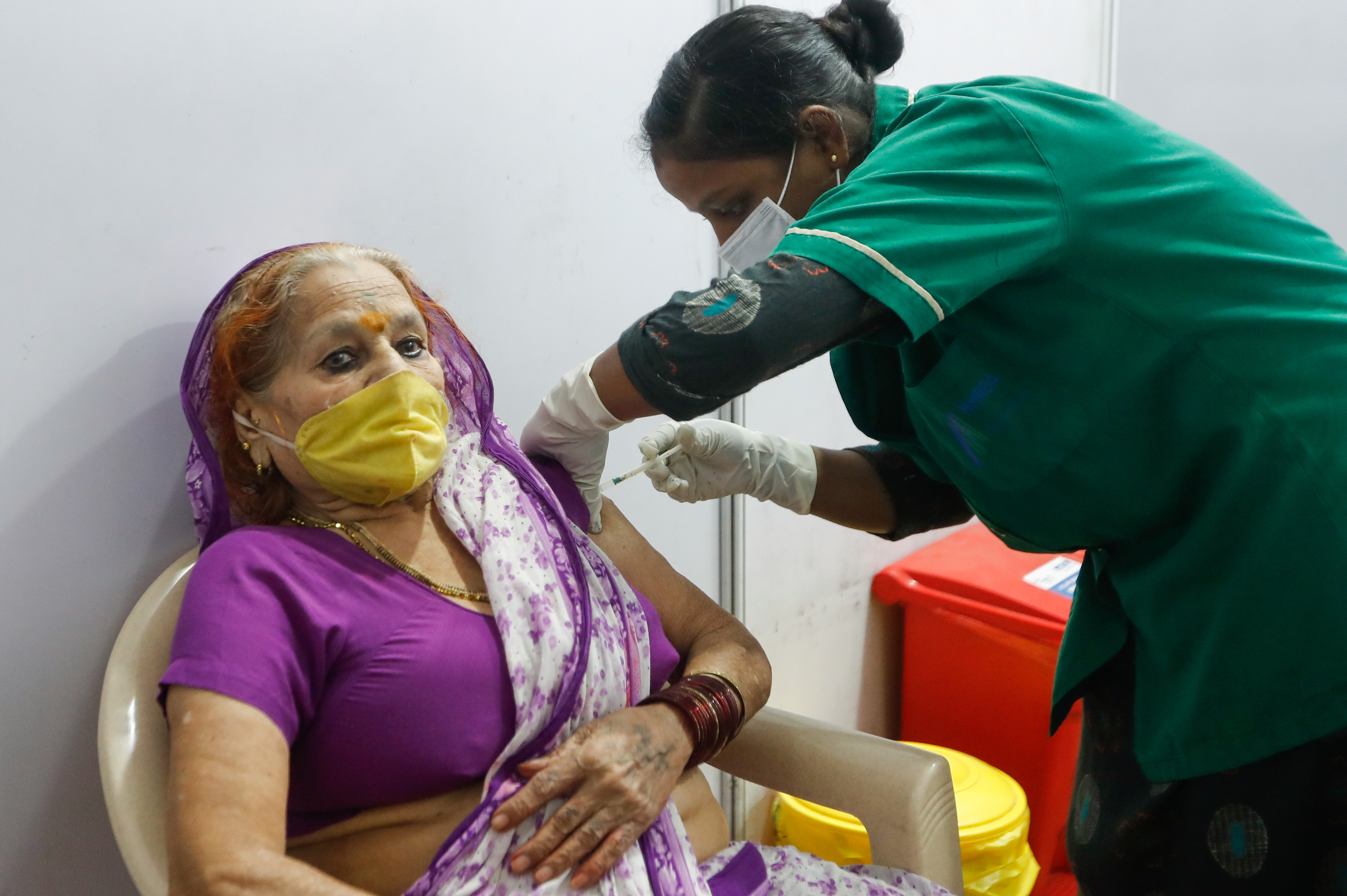 A woman reacts as she receives a dose of COVISHIELD, a COVID-19 vaccine manufactured by Serum Institute of India, in Mumbai