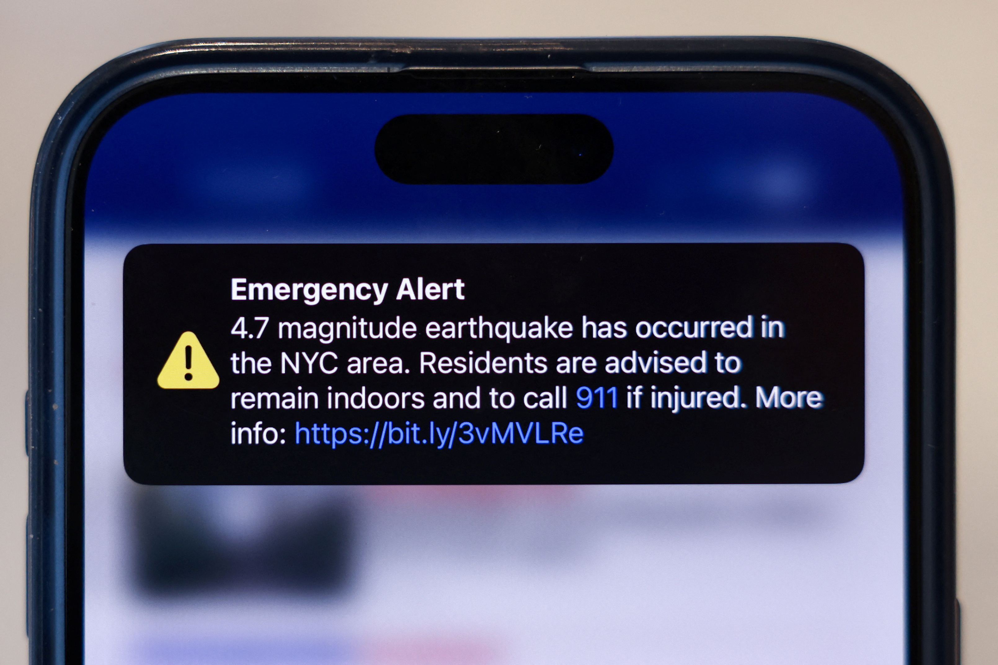 An emergency alert of a magnitude 4.7 earthquake is seen on a cellphone in New York City