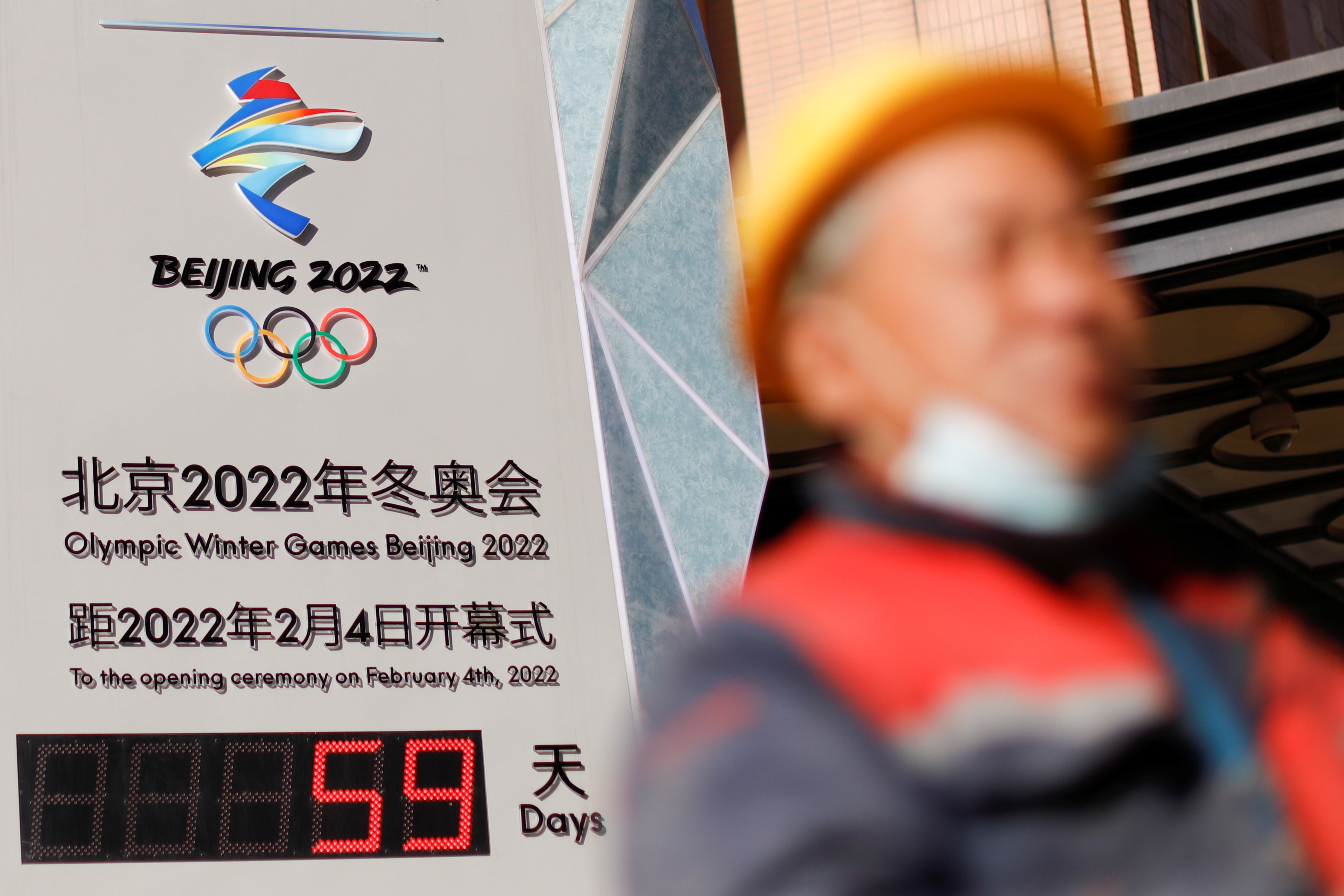 A worker walks past a countdown clock for the Beijing 2022 Winter Olympic Games in Beijing, China December 7, 2021. REUTERS/Carlos Garcia Rawlins