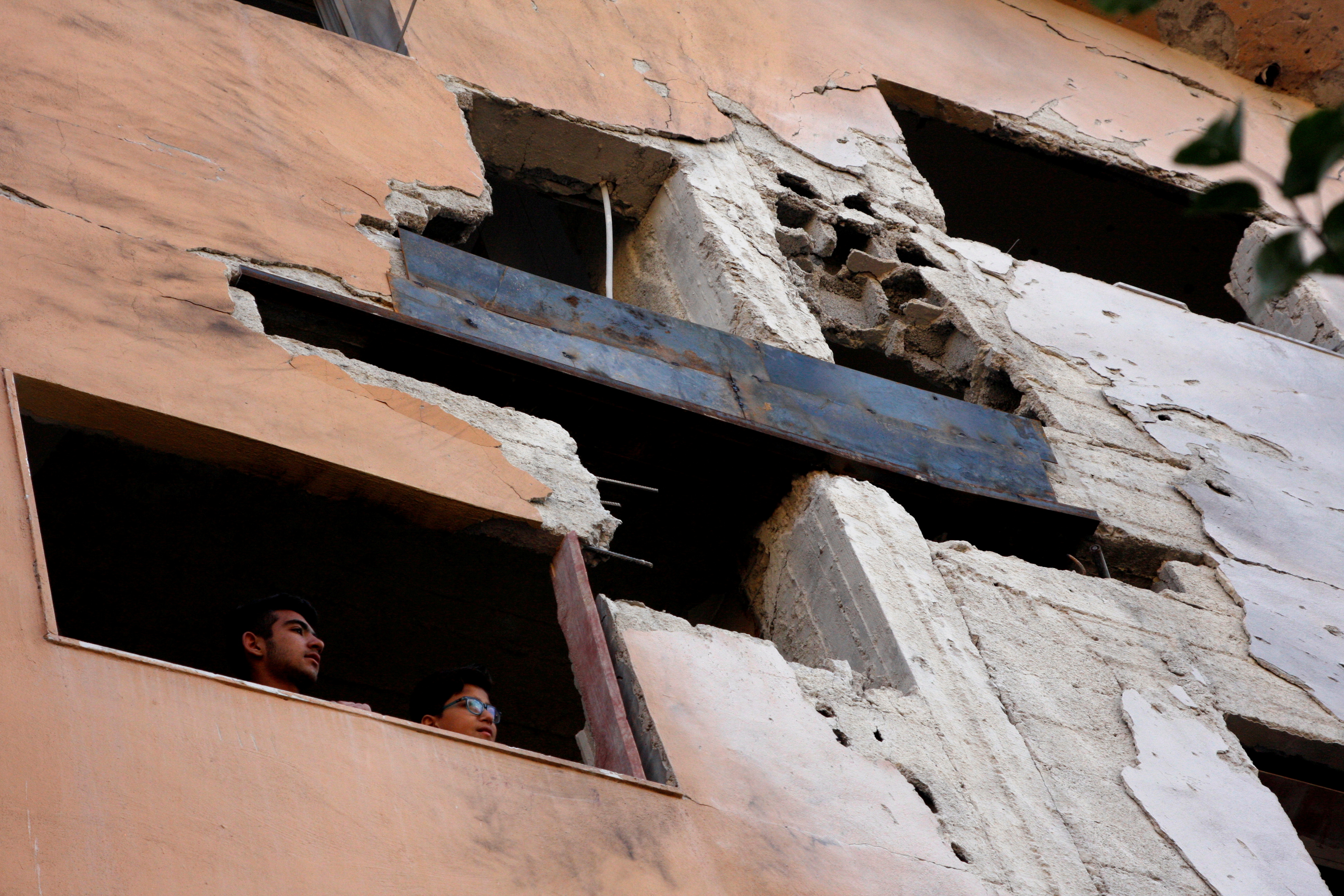 Boys look out the window of a building damaged by an Israeli air strike near Damascus airport, in Damascus, Syria