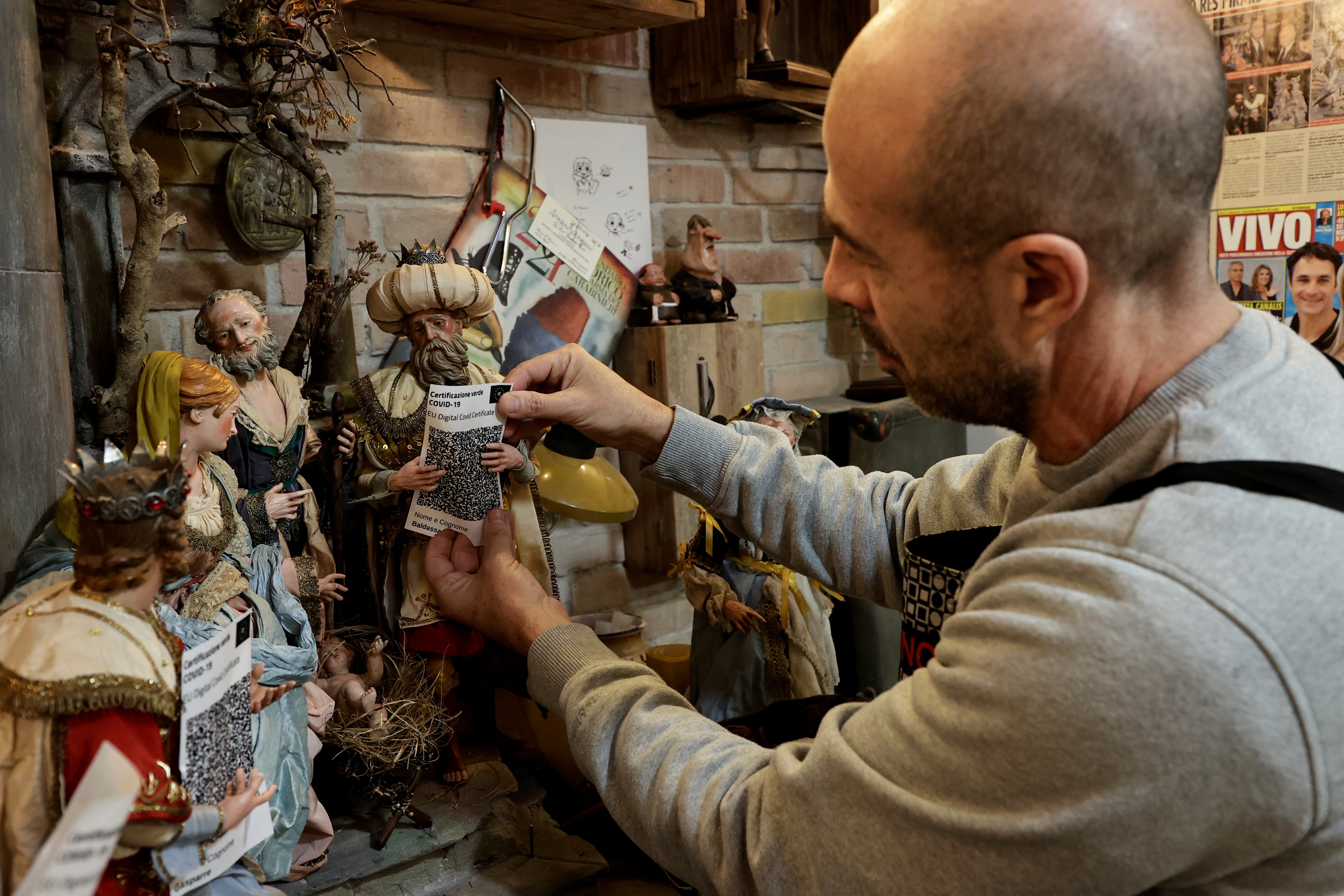 Craftsman Marco Ferrigno works on Christmas nativity figurines, including the three wise men showing their COVID-19 health passes, in Naples, Italy November 3, 2021. REUTERS/Ciro De Luca