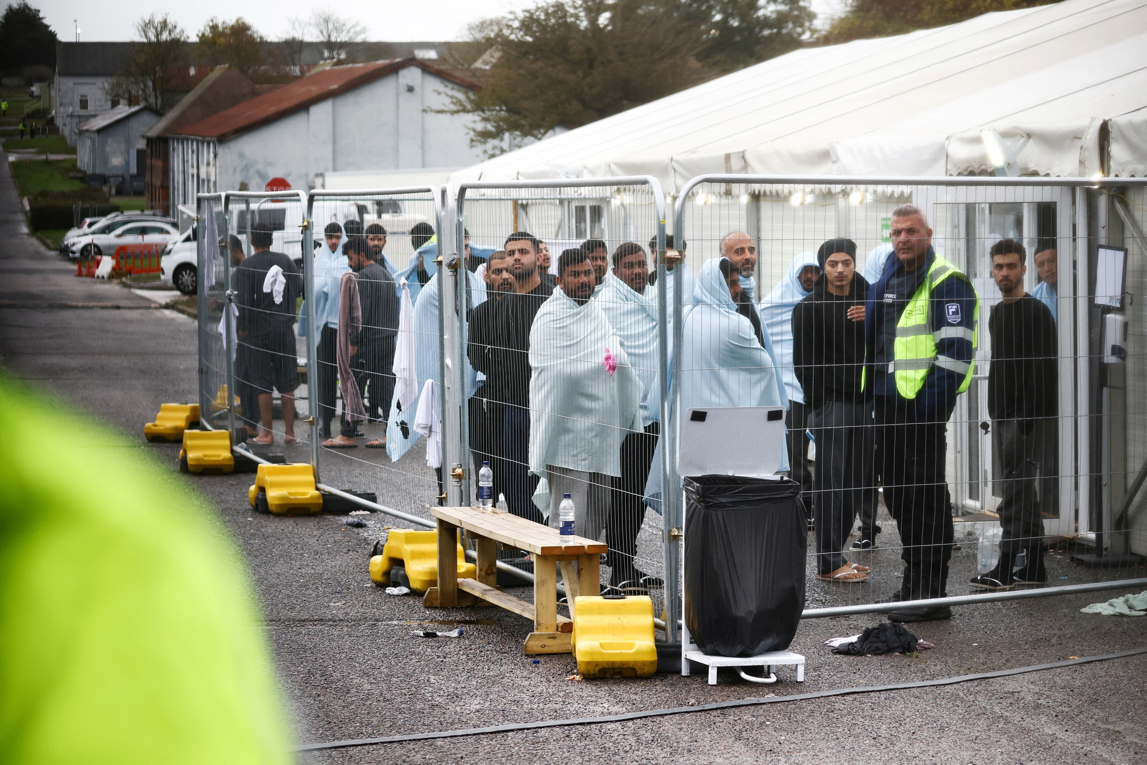 People stand inside a fenced off area inside the migrant processing centre in Manston