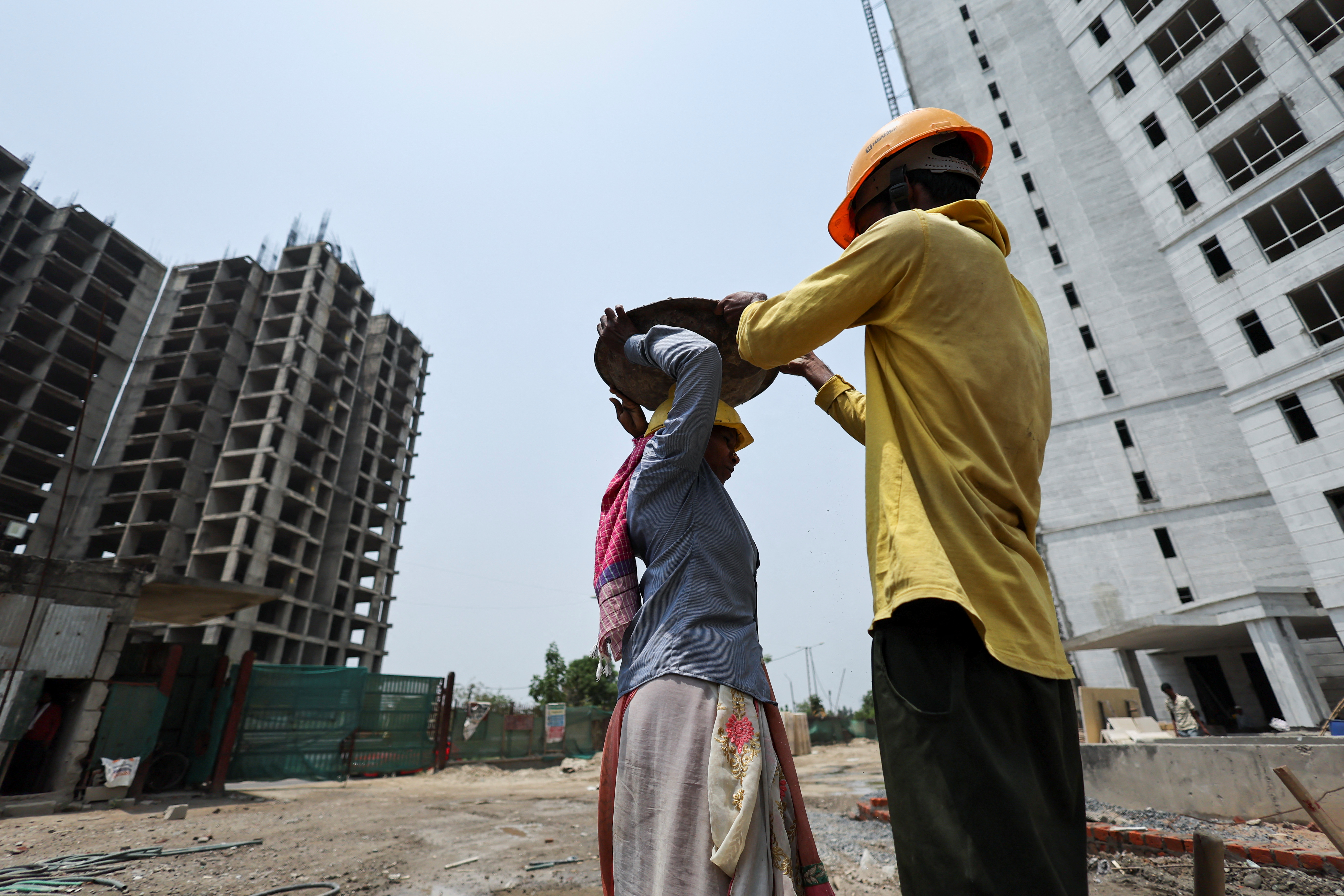 Labourers work at a construction site on a hot summer day, in Noida