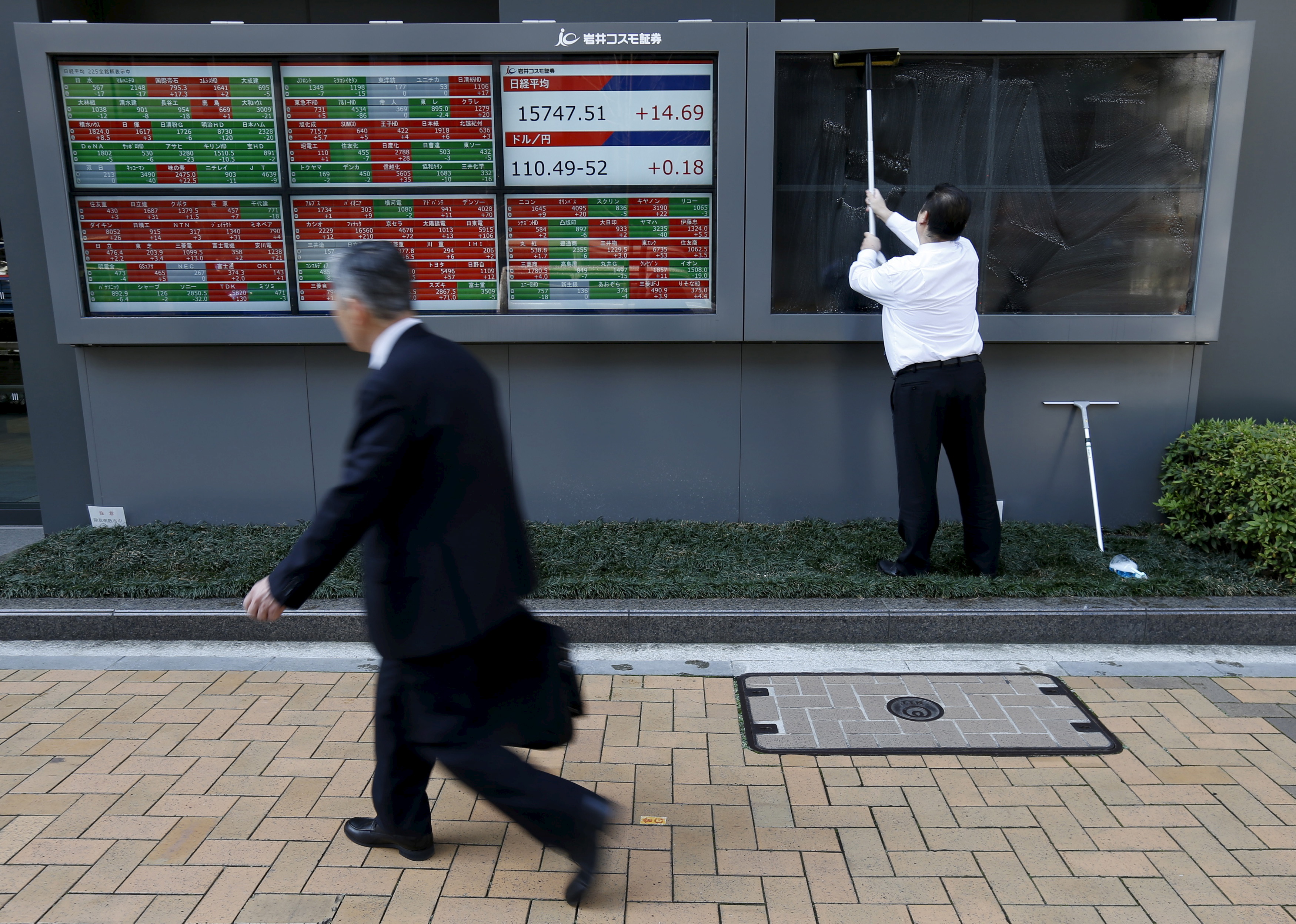 A man cleans electronic boards showing the Japan's Nikkei average, the exchange rate between Japanese yen against the U.S. dollar and stock quotation outside a brokerage in Tokyo