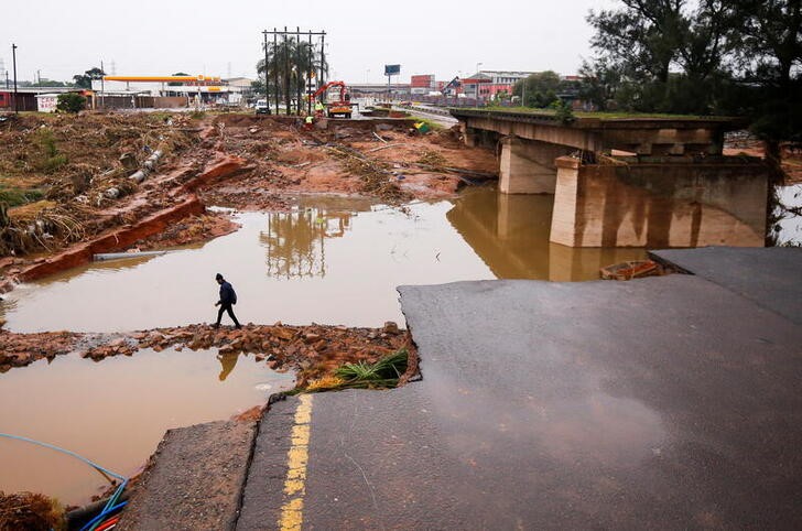 A man walks around a damaged bridge caused by flooding in Umlazi near Durban