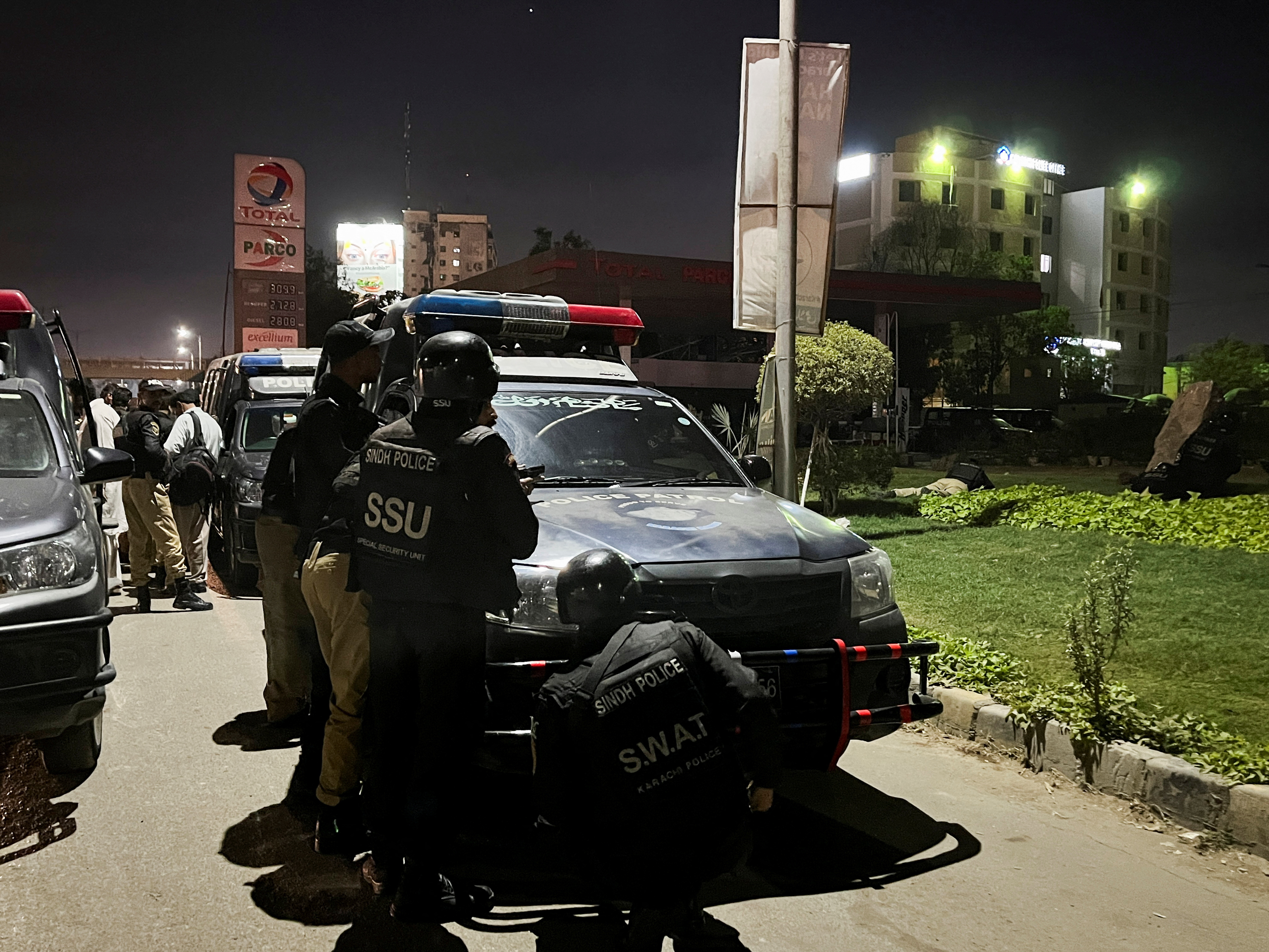 Police officers take position after a police office building was attacked by gunmen in Karachi