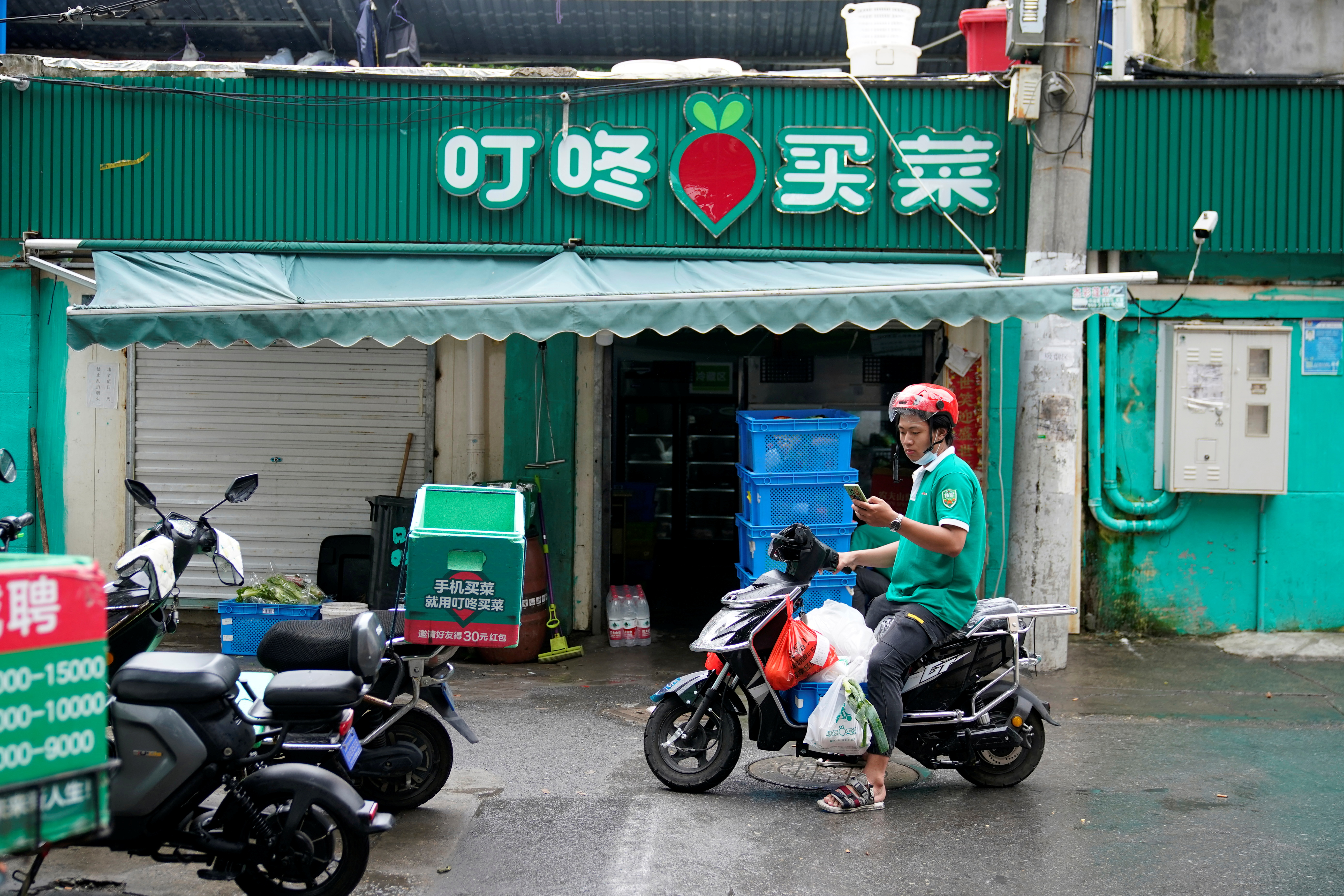 A delivery worker of Chinese online grocery Dingdong Maicai works at a shop on a street in Shanghai