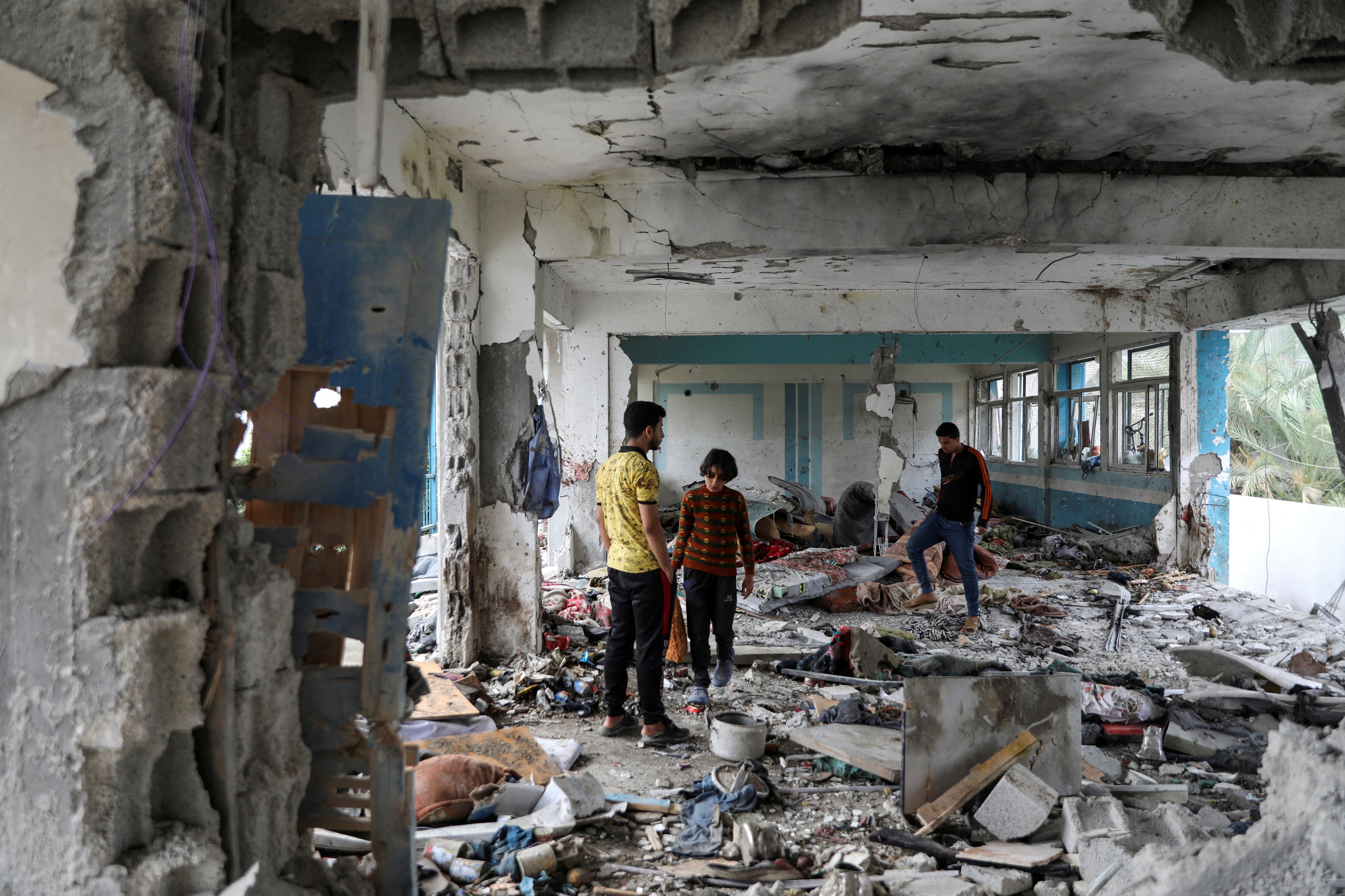Palestinians inspect the site of an Israeli strike on a UNRWA school sheltering displaced people, in Nuseirat refugee camp