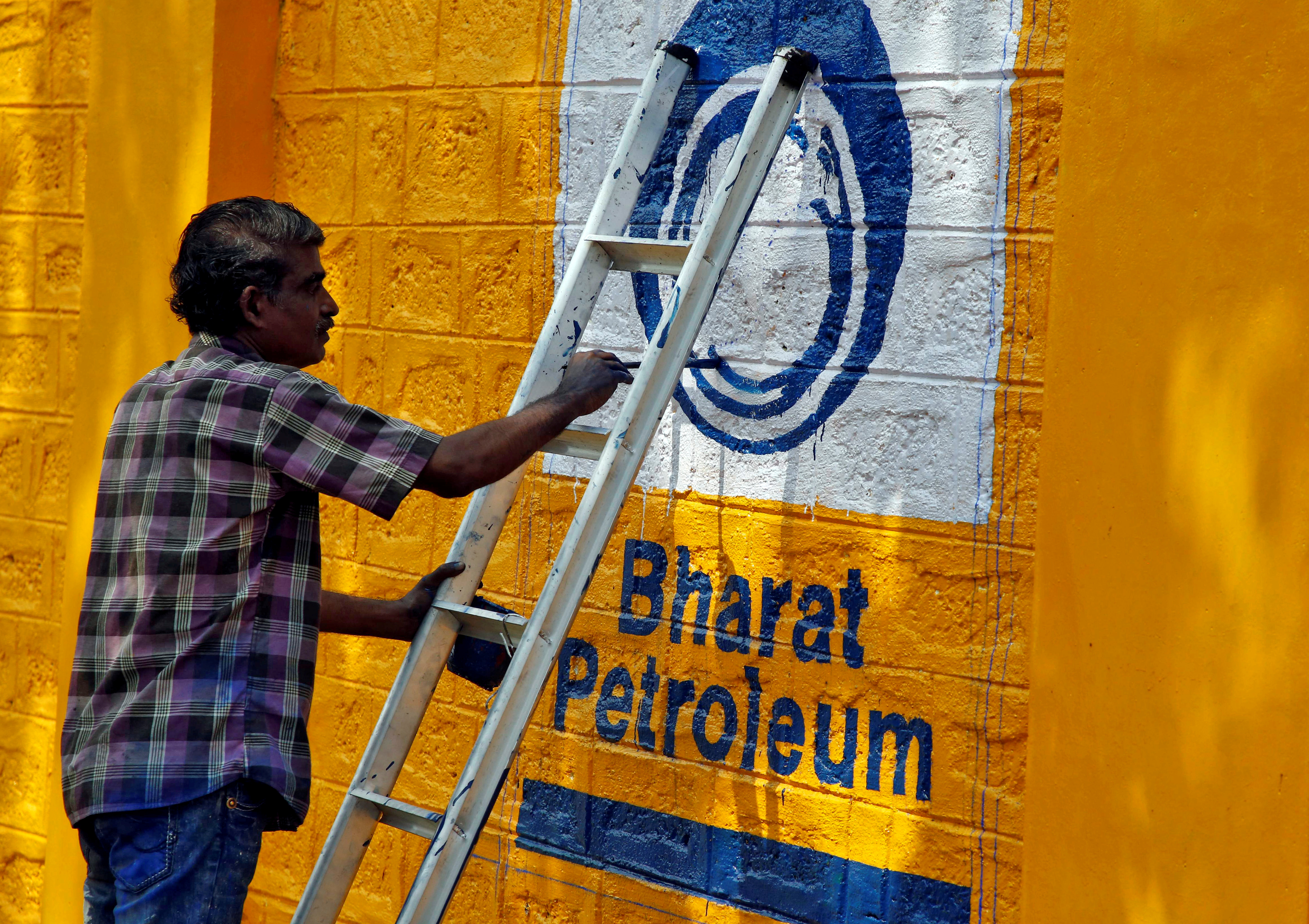 A man paints the logo of oil refiner Bharat Petroleum Corp on a wall on the outskirts of Kochi