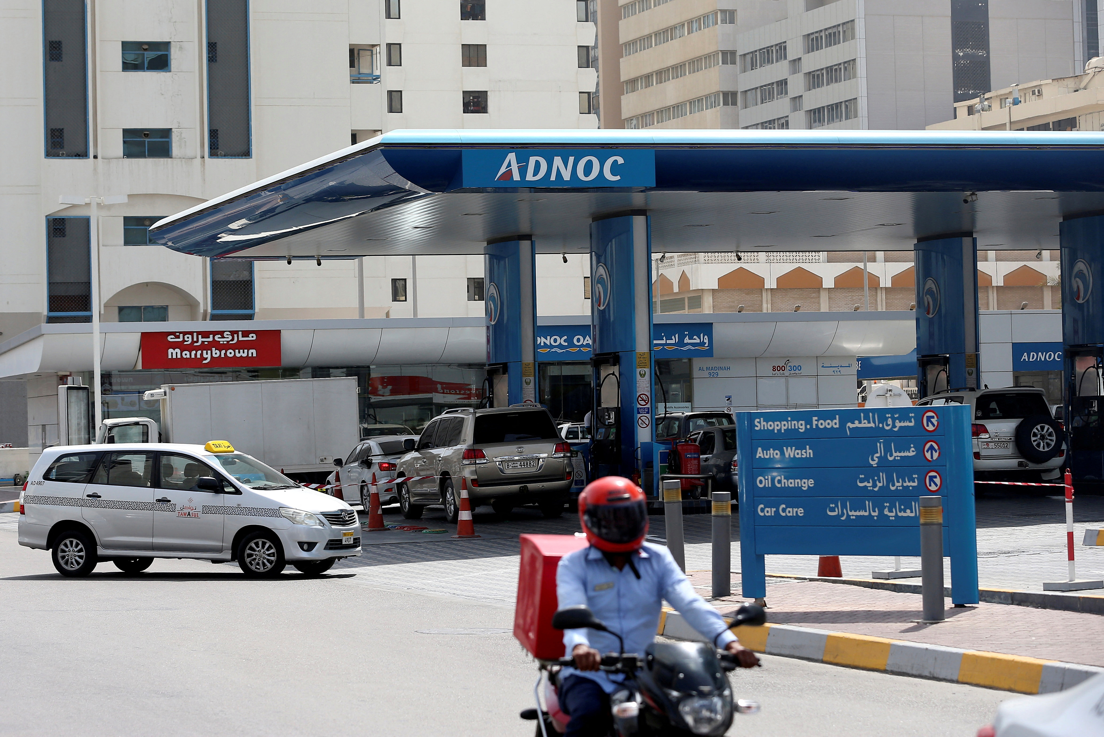 Man rides a motorcycle near an ADNOC petrol station in Abu Dhabi