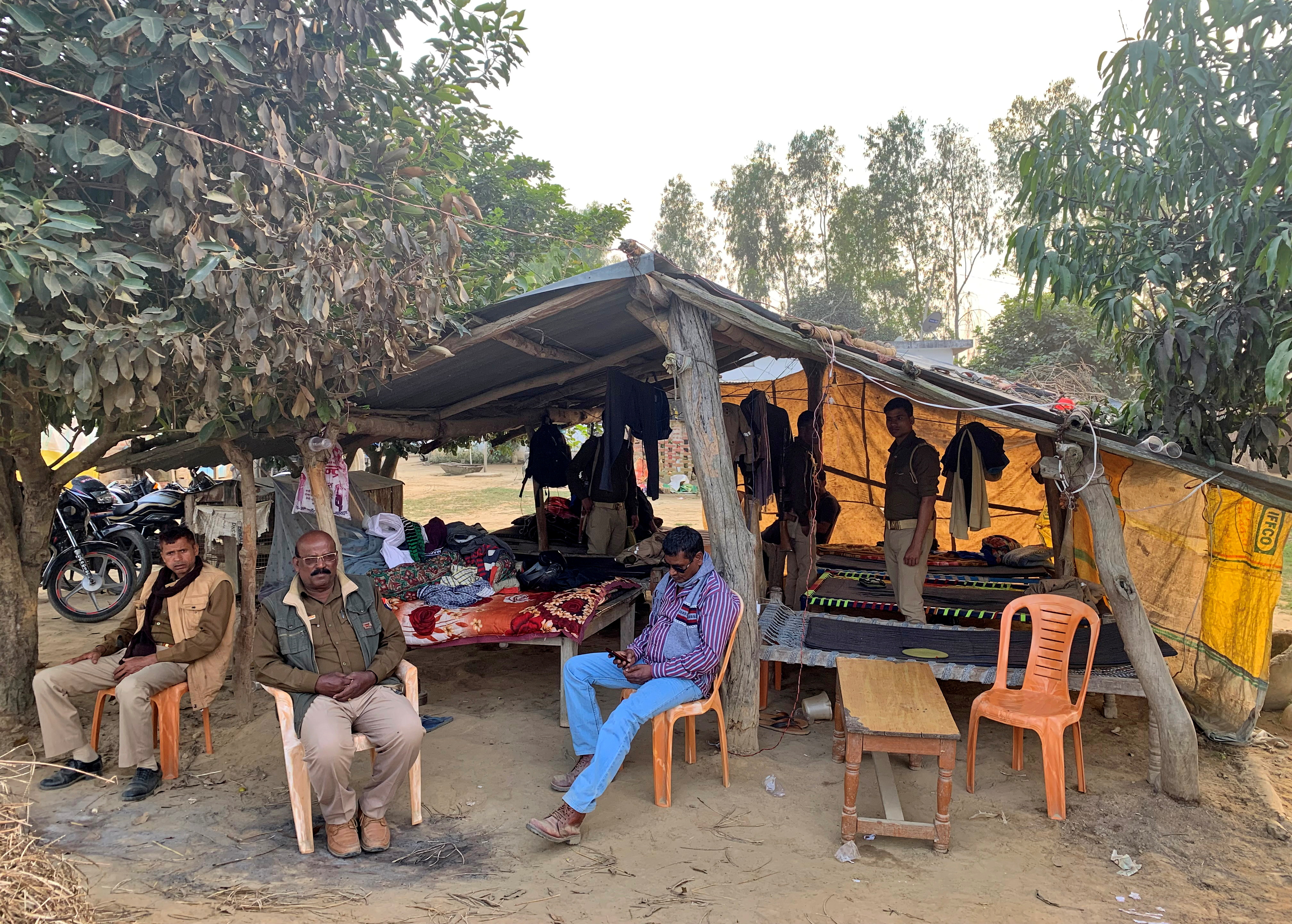 Police officers sit outside their makeshift post that was set up to guard the house of Guru Sevak Singh, a farmer, after his brother Guruvinder Singh was killed during a farmers' protest in Lakhimpur Kheri last month, in Mohraniya village of the Bahraich district in the northern state of Uttar Pradesh, India, November 19, 2021. REUTERS/Saurabh Sharma 