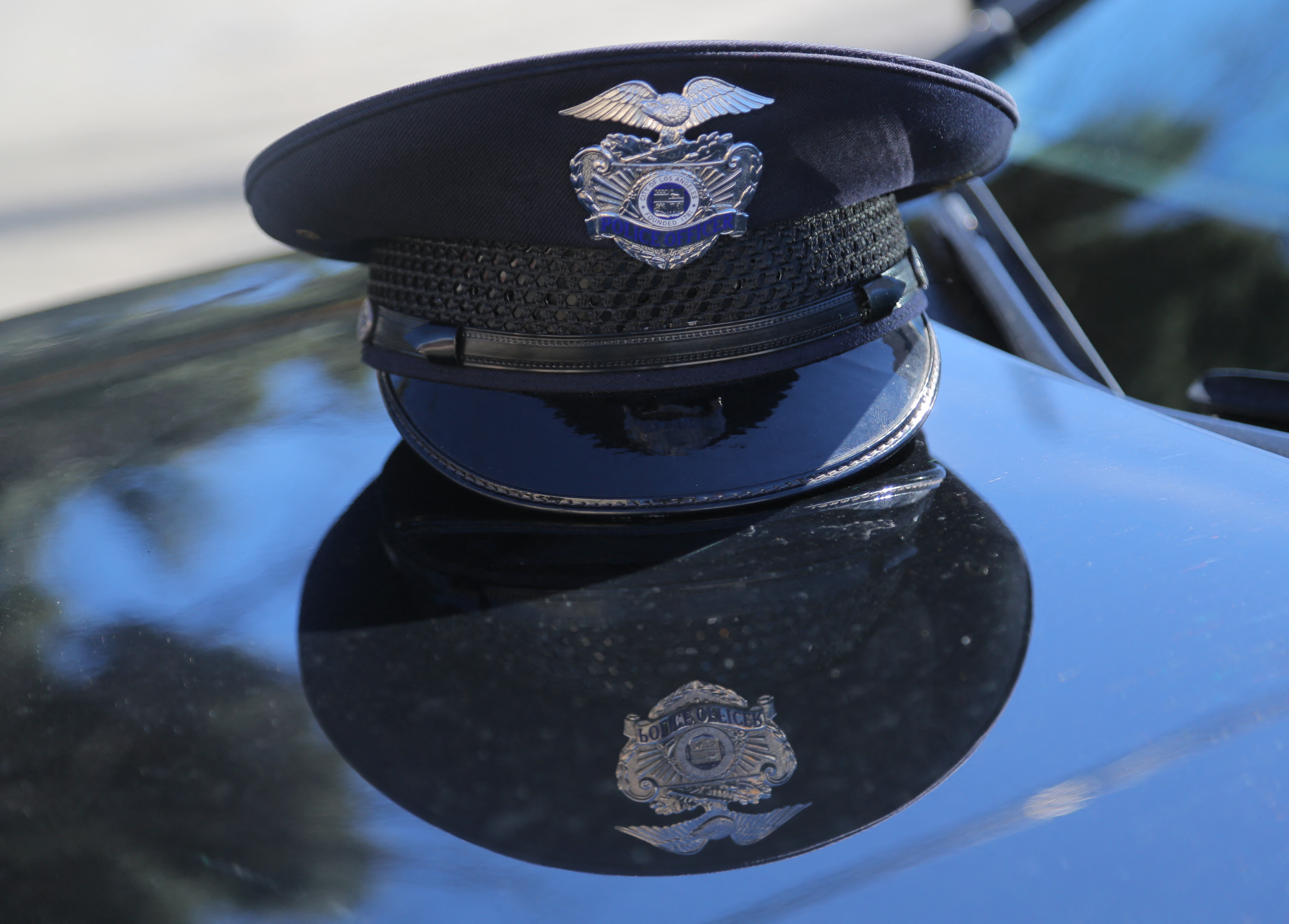 A Los Angeles Police Department (LAPD) officer's cap rests on the hood of a patrol vehicle in Los Angeles