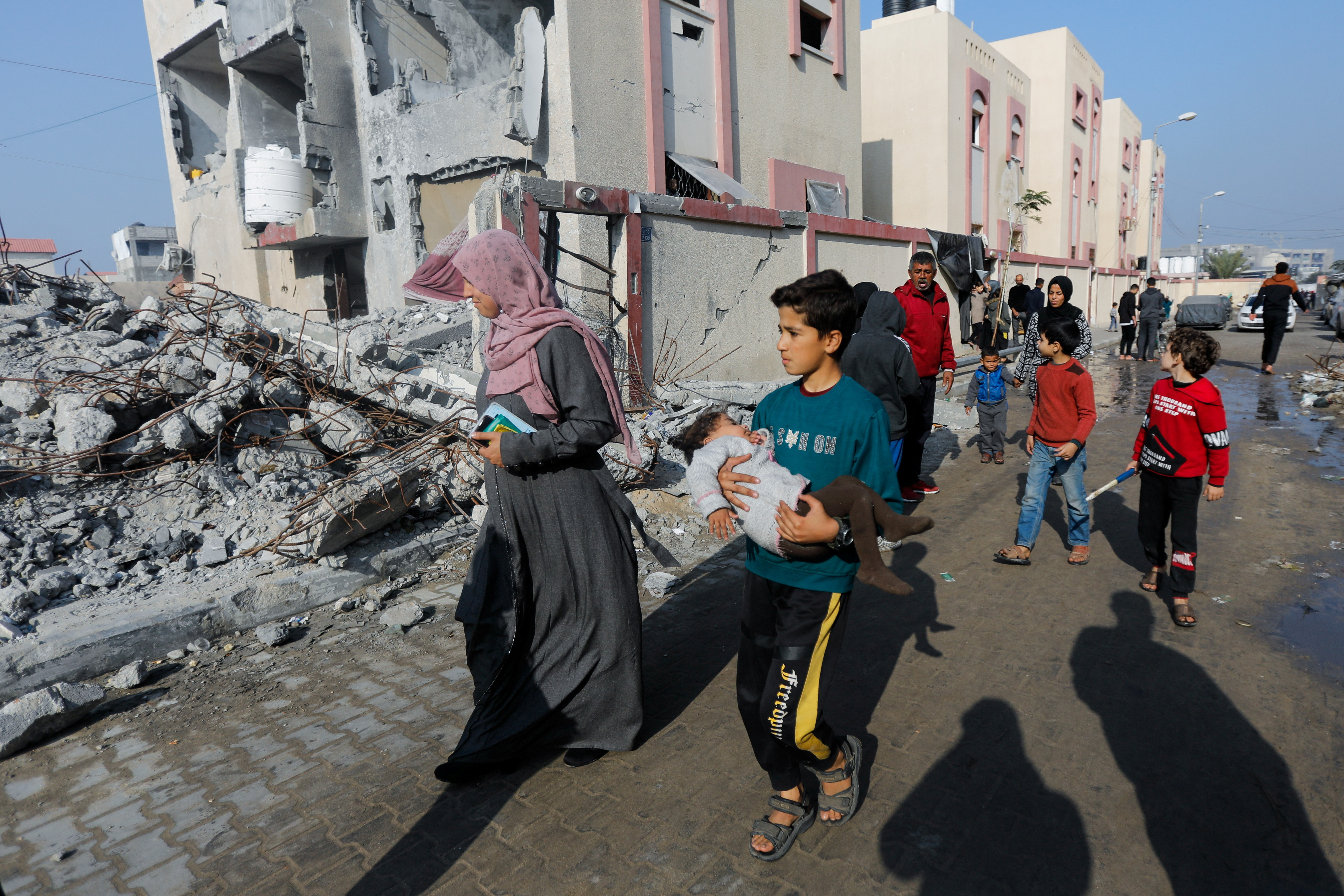 Palestinians walk past houses destroyed by an Israeli strike, in Rafah