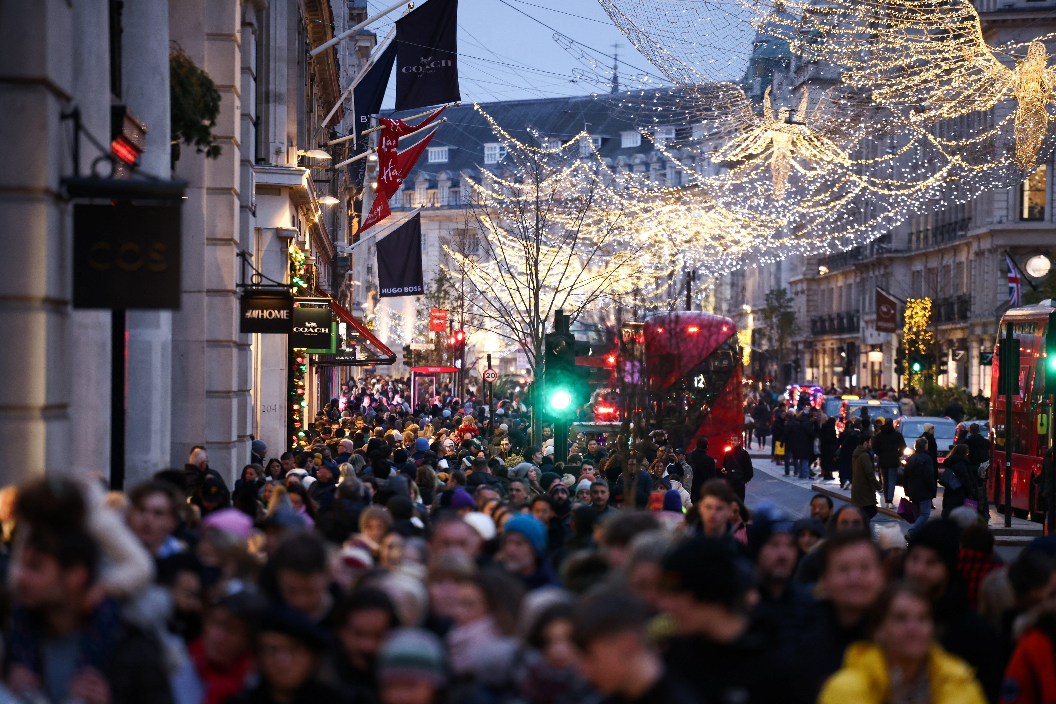 People carry shopping bags as they walk past Christmas themed shop displays on Regent Street in London