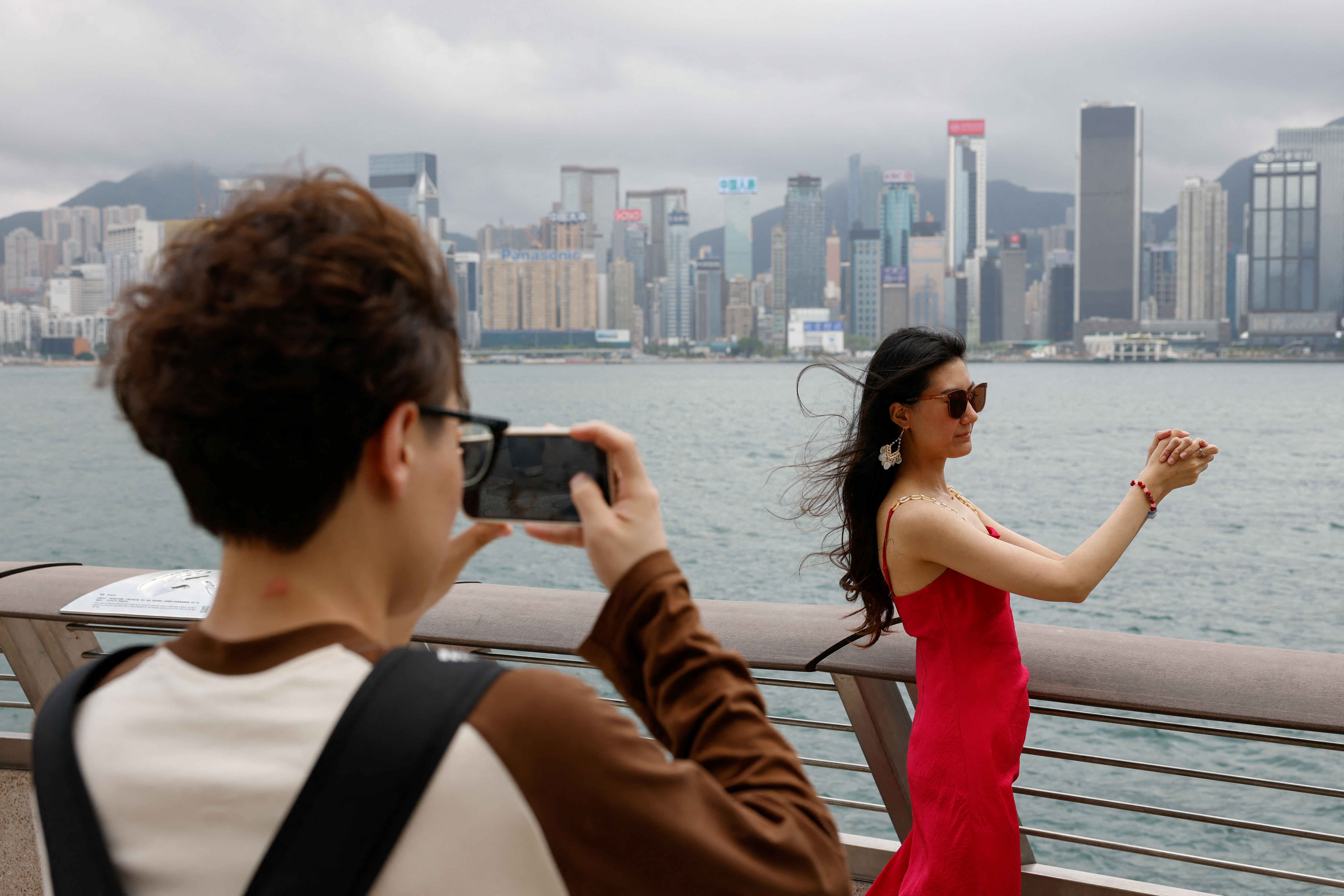 Laura Li, 28, poses for photos in front of Victoria Harbour, a day ahead of the Chinese Labour Day 'Golden Week' holidays, in Hong Kong