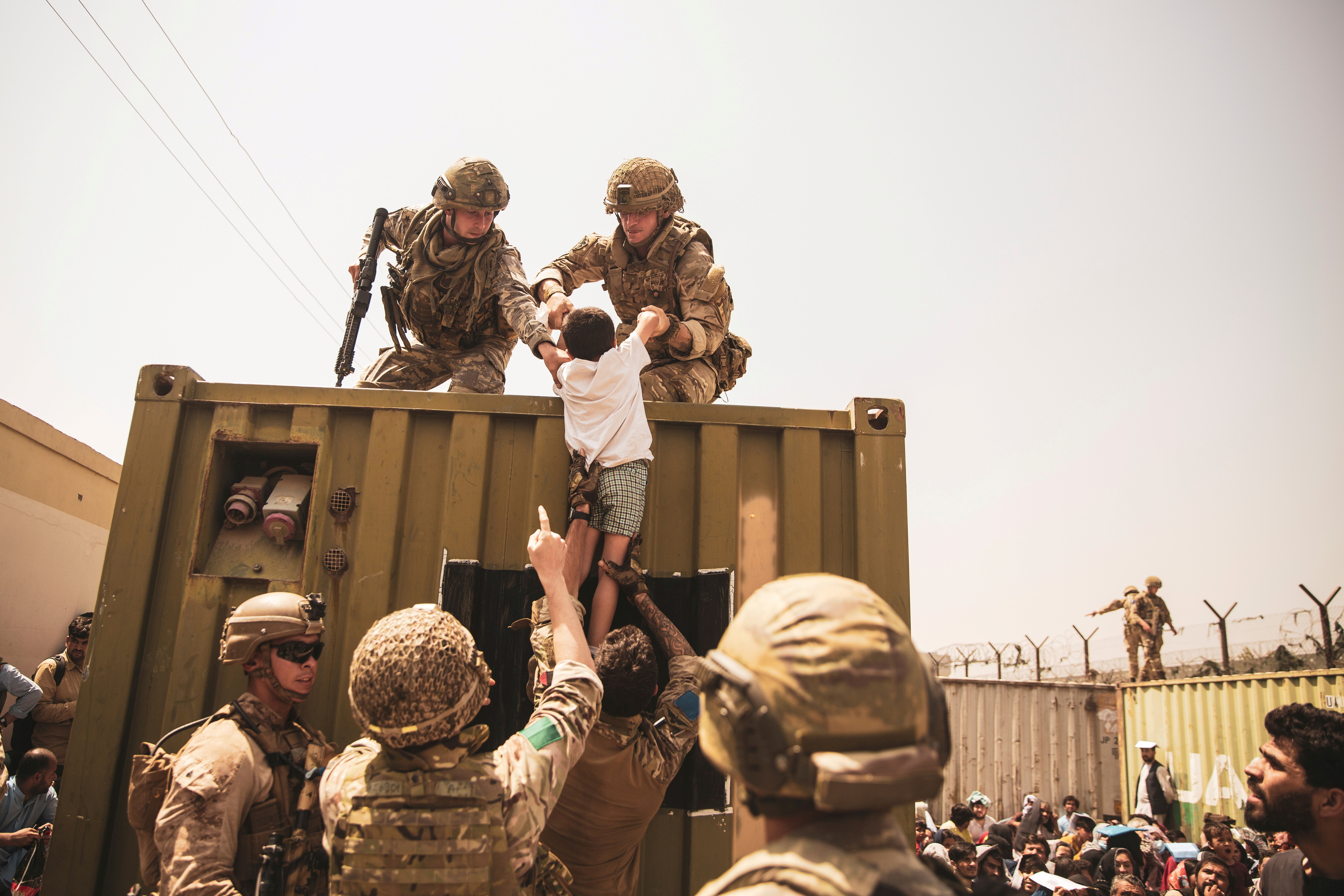 UK coalition forces, Turkish coalition forces, and U.S. Marines assist a child during an evacuation at Hamid Karzai International Airport, Kabul