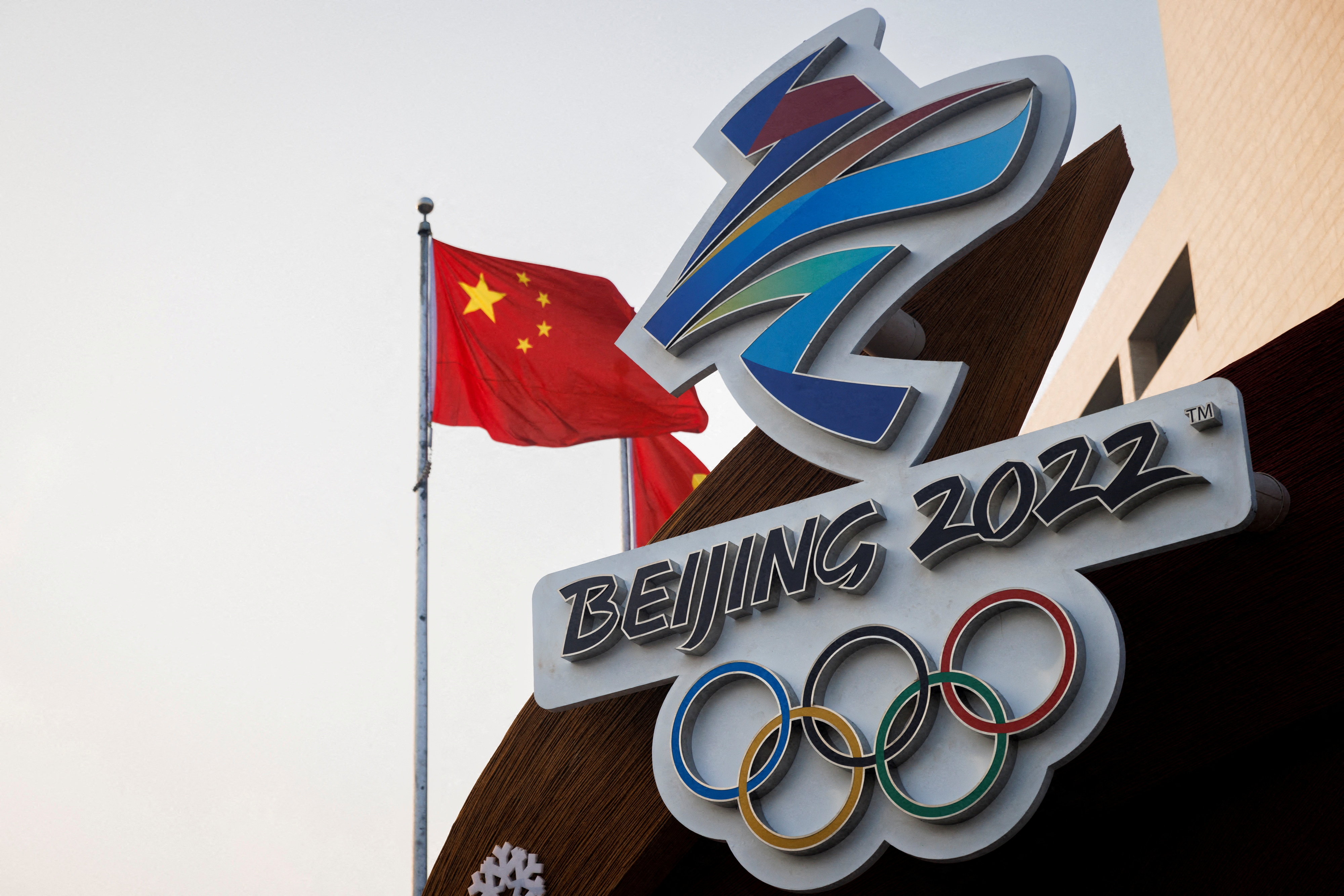 The Chinese national flag flies behind the logo of the Beijing 2022 Winter Olympics in Beijing