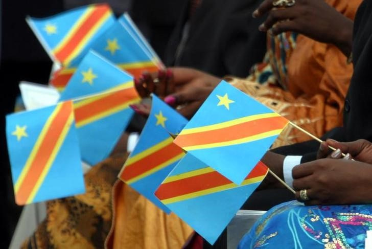 Congolese ladies hold paper replicas of Democratic Republic of Congo's new flag during ceremony in Kinshasa