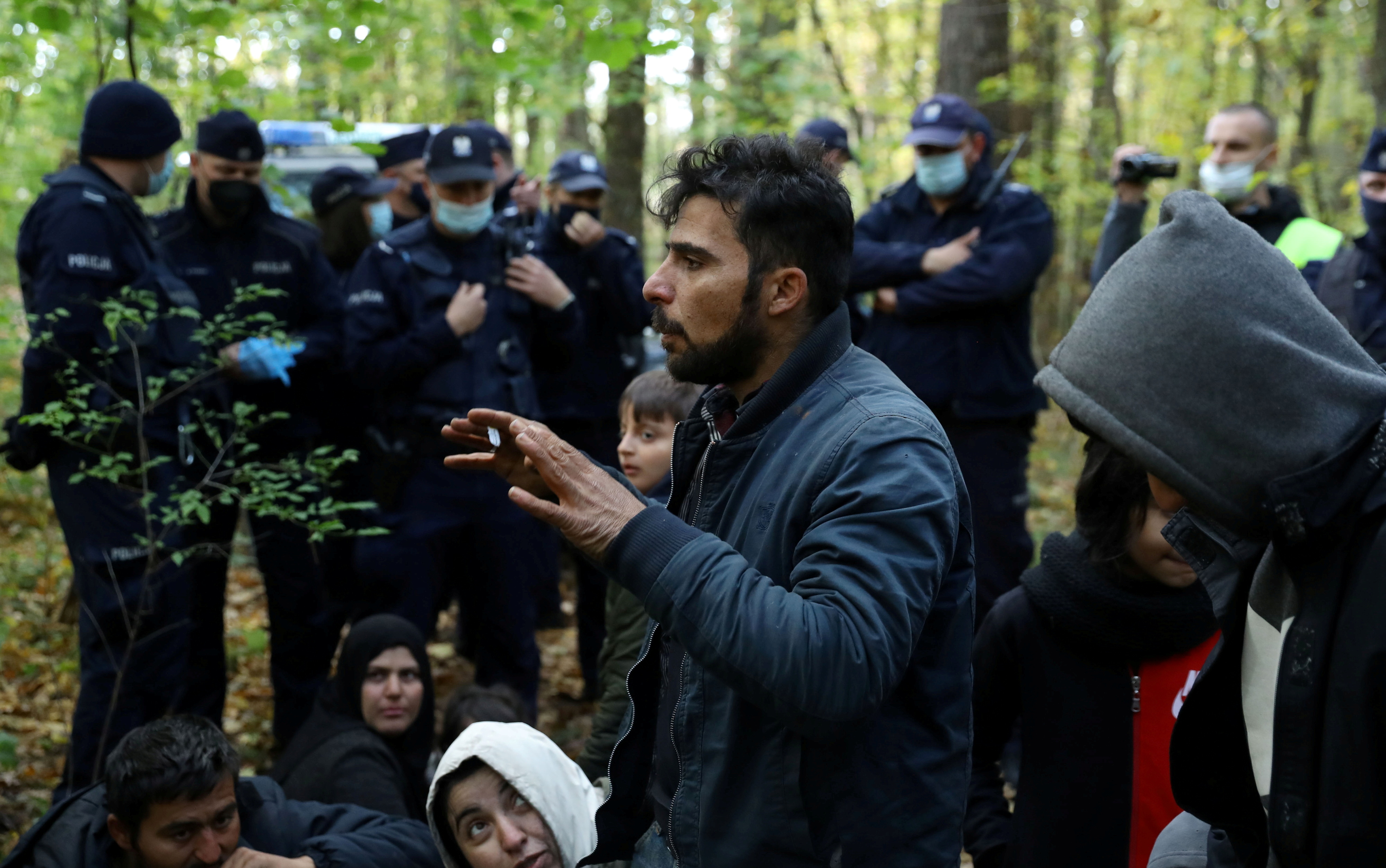 Iraqi migrants talk to NGO Grupa Granica's representatives as they are surrounded by border guards and police officers after they crossed the Belarusian-Polish border during the ongoing migrant crisis, in Hajnowka