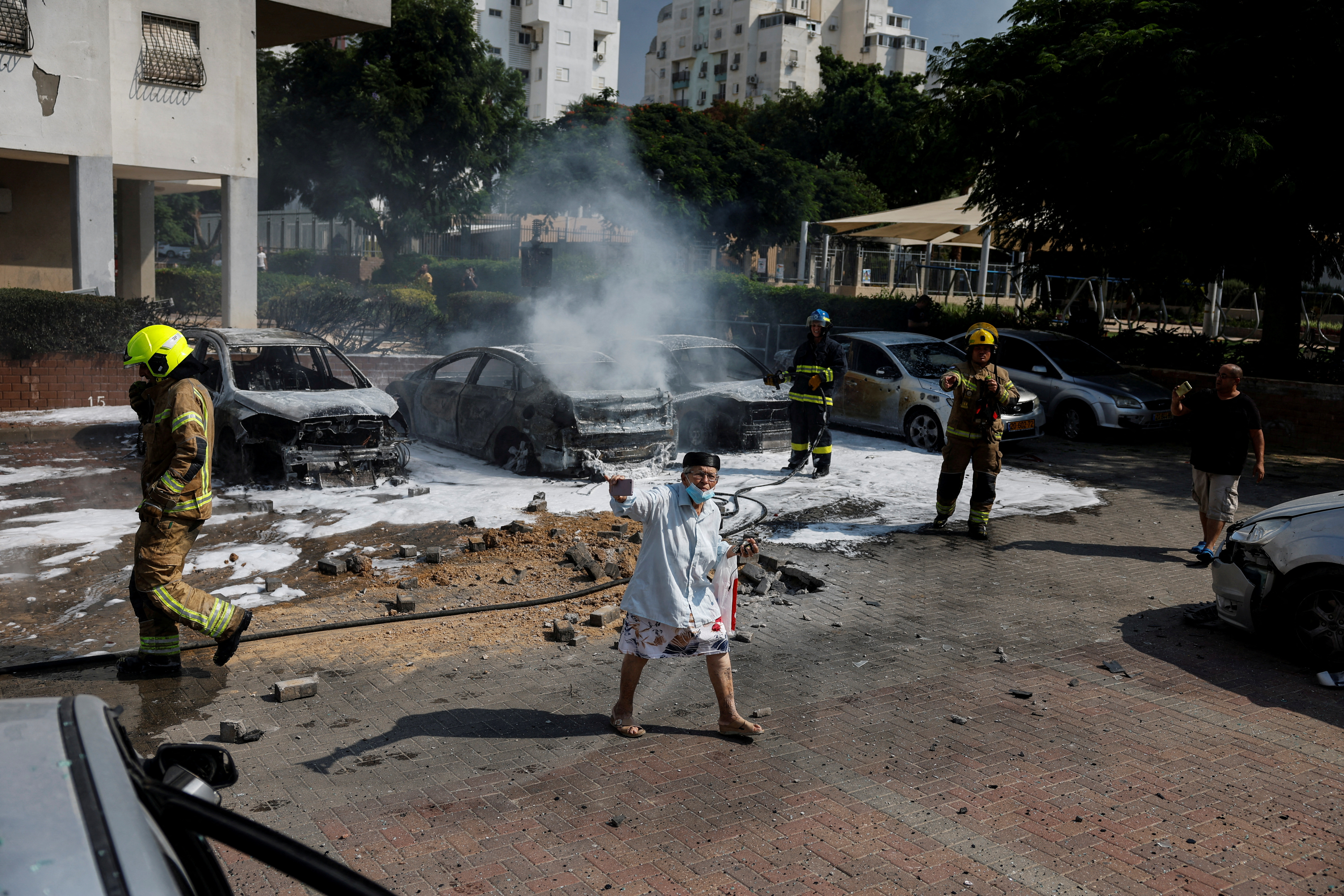 Israeli firefighters work to put out vehicles on fire after a rocket, launched from the Gaza Strip, landed in Ashkelon