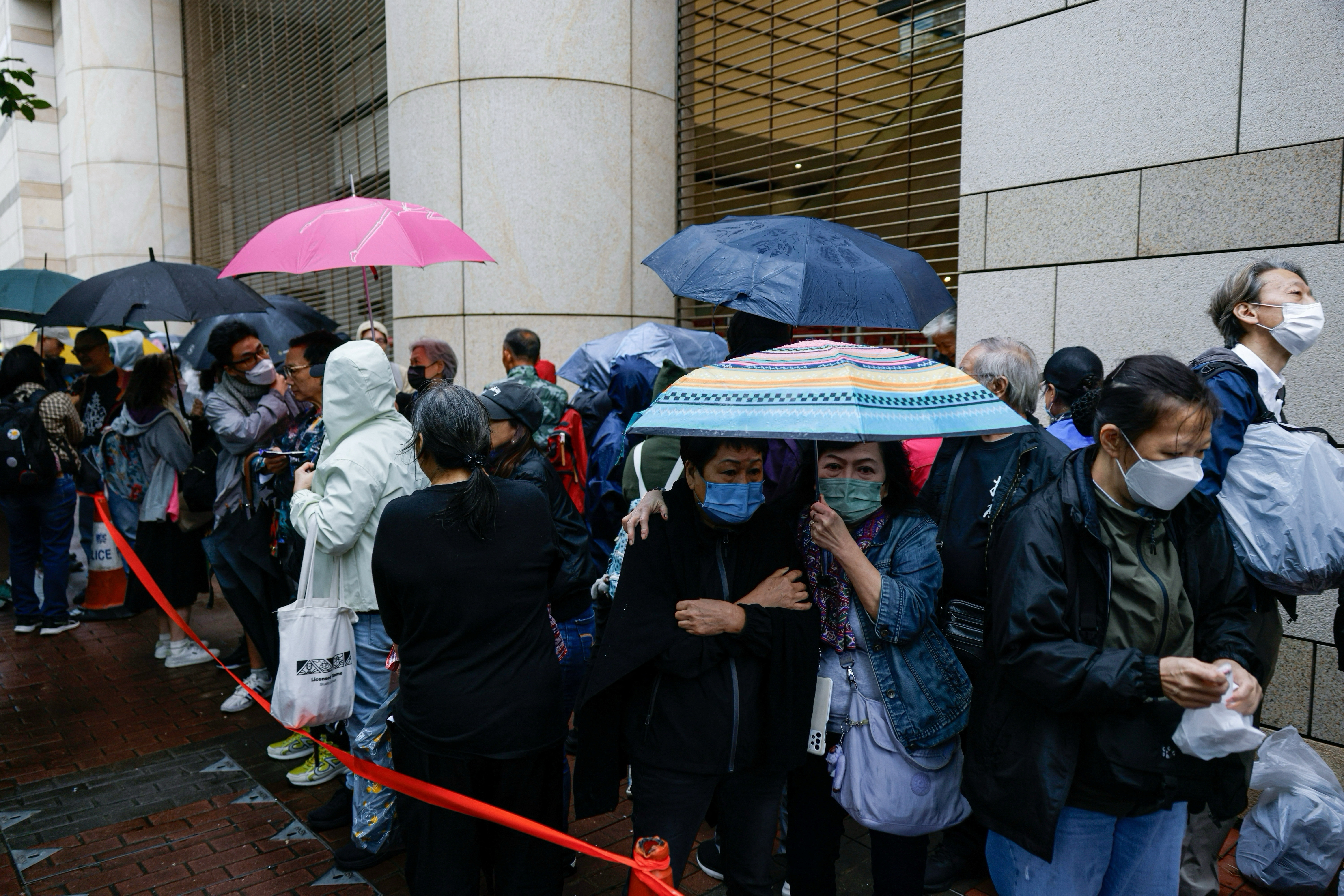 People queue to enter the West Kowloon Magistrates' Courts building, before the sentencing against the 45 convicted pro-democracy activists charged under the national security law, in Hong Kong