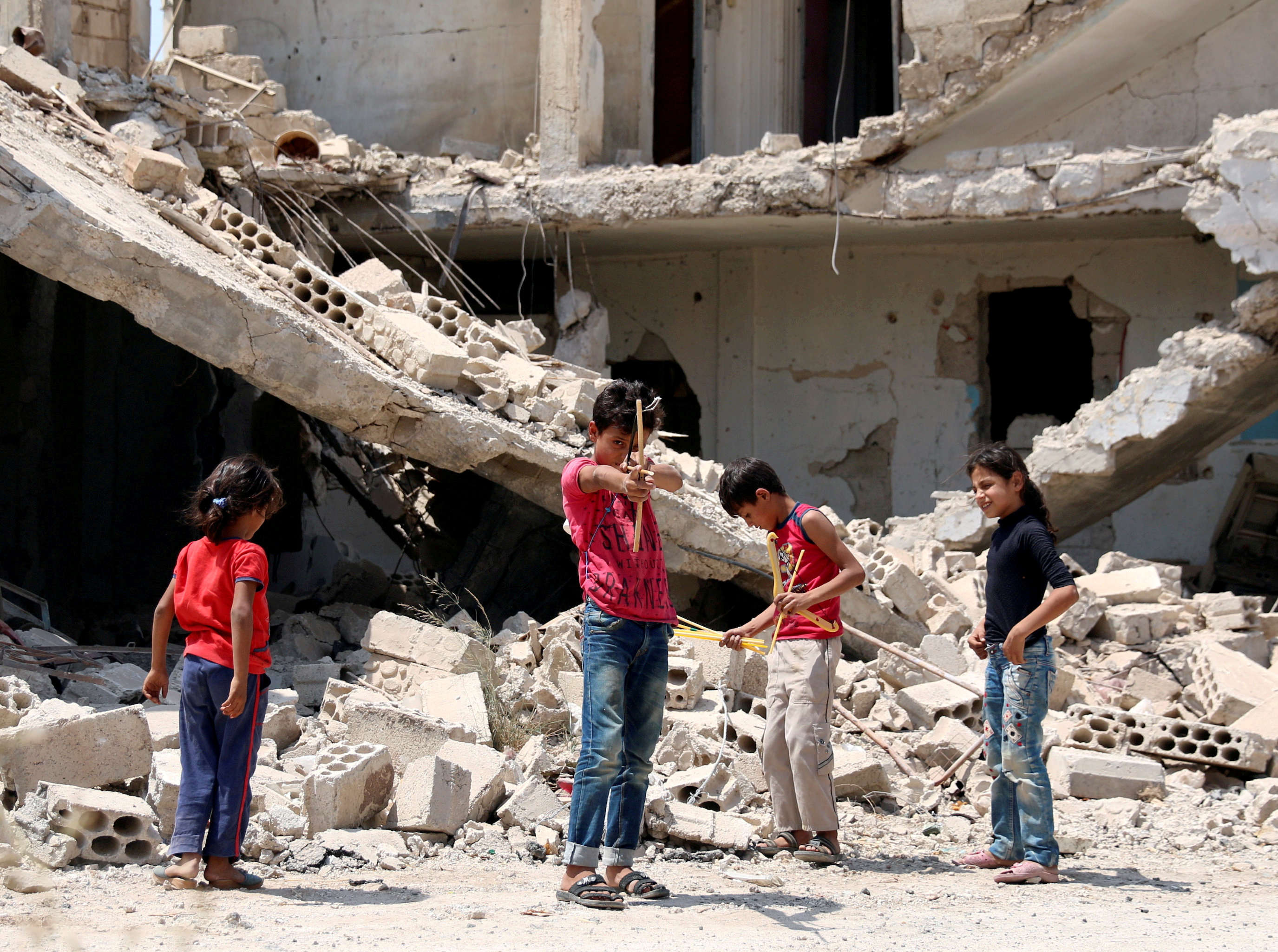 Children play along a street in a rebel-held part of the southern city of Deraa