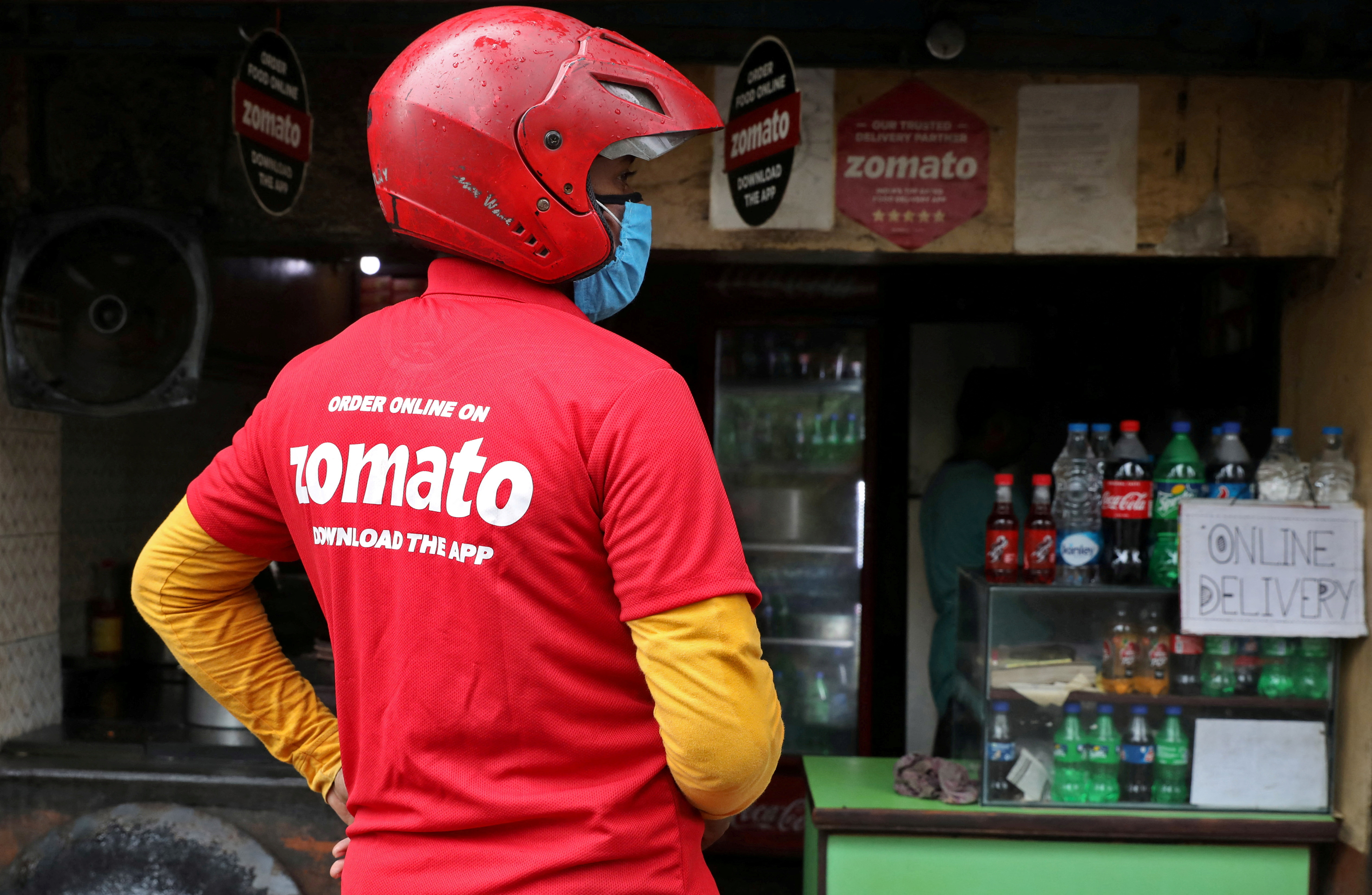 A delivery worker of Zomato waits to collect order outside an eatery in Kolkata