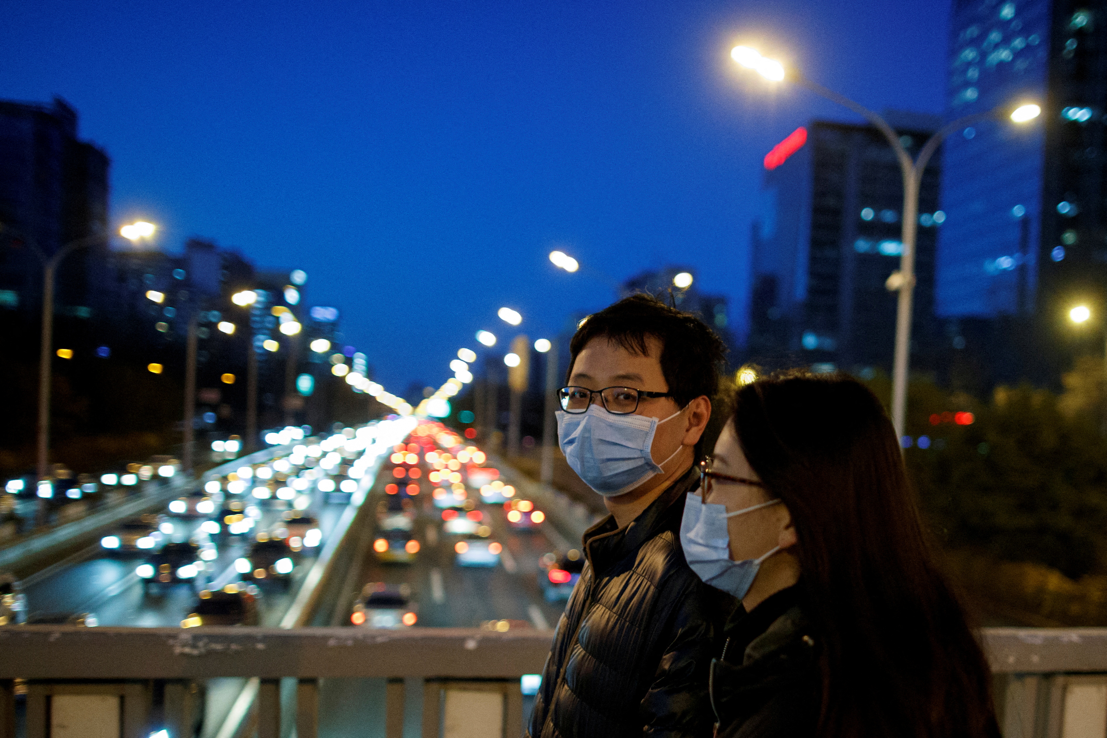 People cross a bridge over a major thoroughfare that is clogged with slow moving traffic during evening rush hour, as the country is hit by an outbreak of the novel coronavirus, in Beijing, China, March 3, 2020. REUTERS/Thomas Peter/File Photo