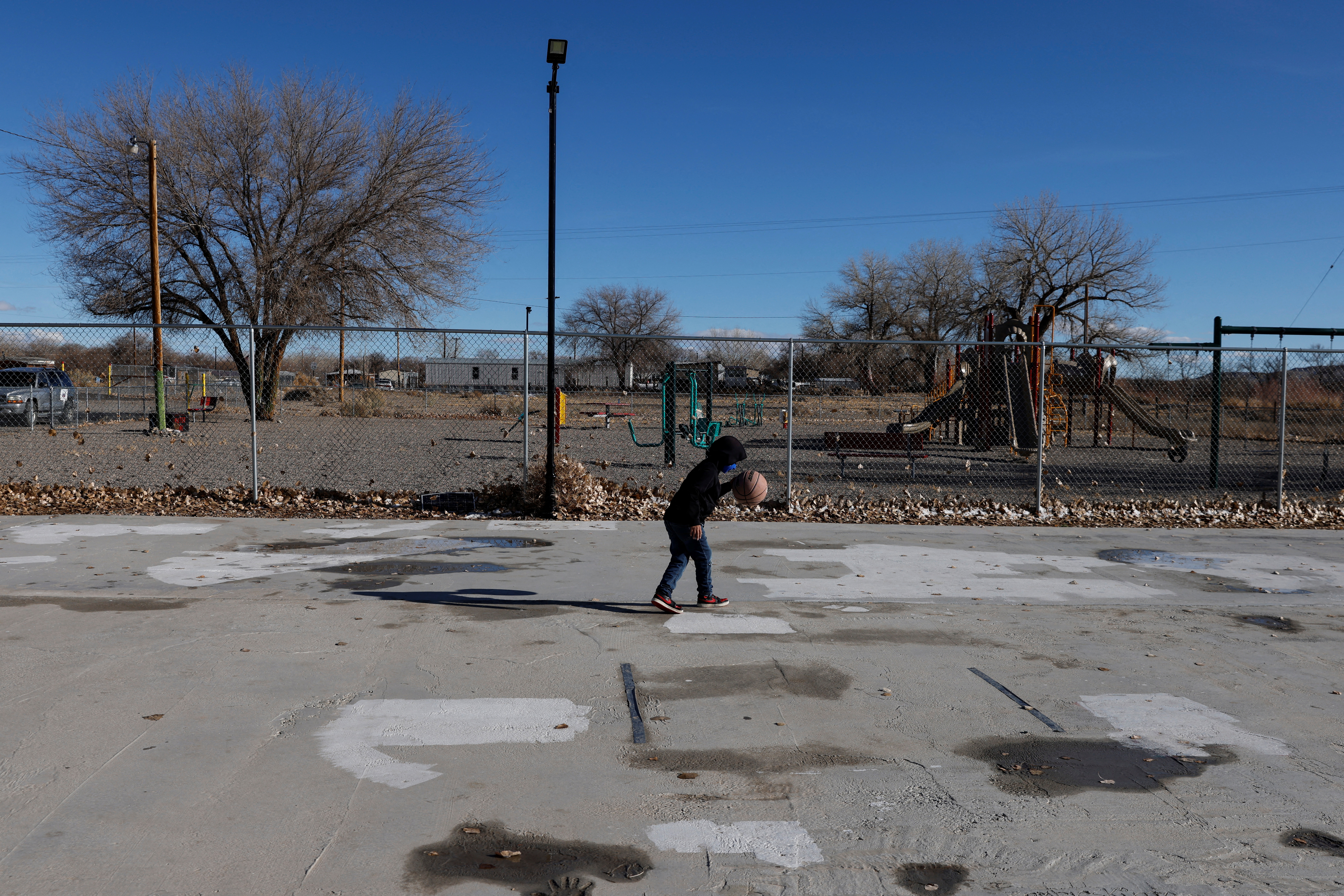 A  boy wearing a protective face mask, amid the coronavirus disease (COVID-19) pandemic, dribbles on a basketball court in Shiprock, New Mexico