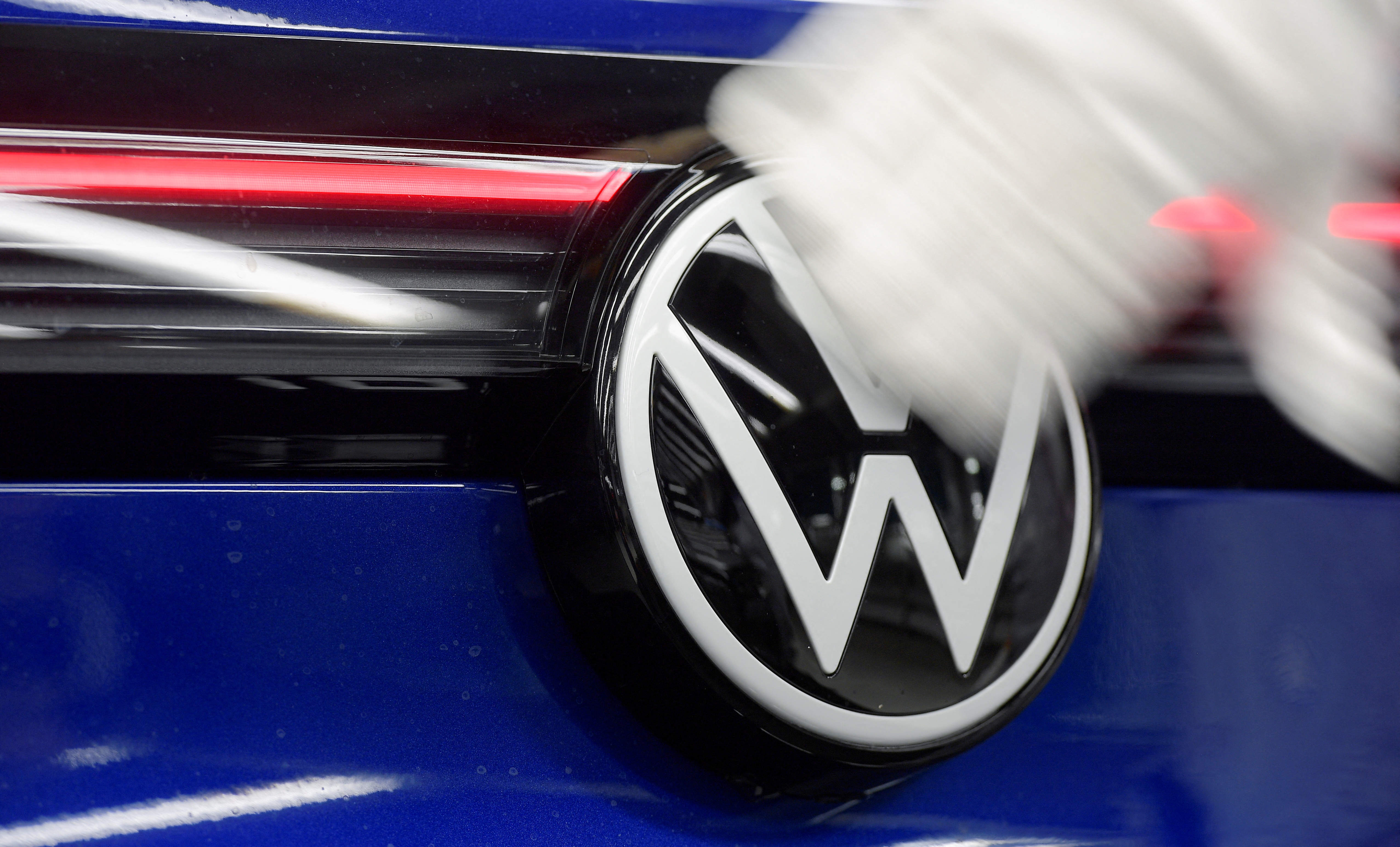 A technician cleans a Volkswagen logo at the production line for electric car models of the Volkswagen Group, in Zwickau