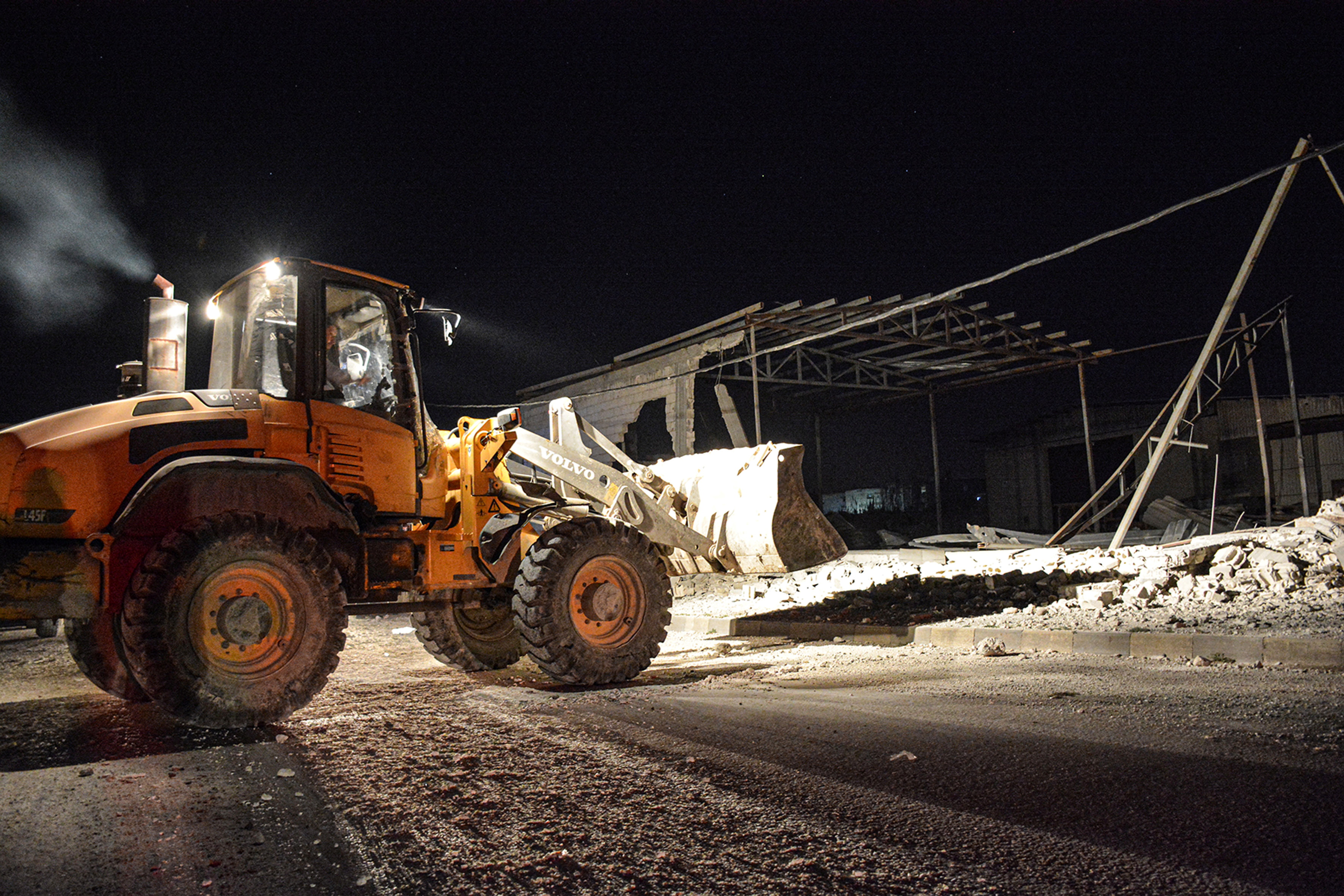 A man operates a front loader at a site after pre-dawn raids on the Mediterranean port region of Latakia