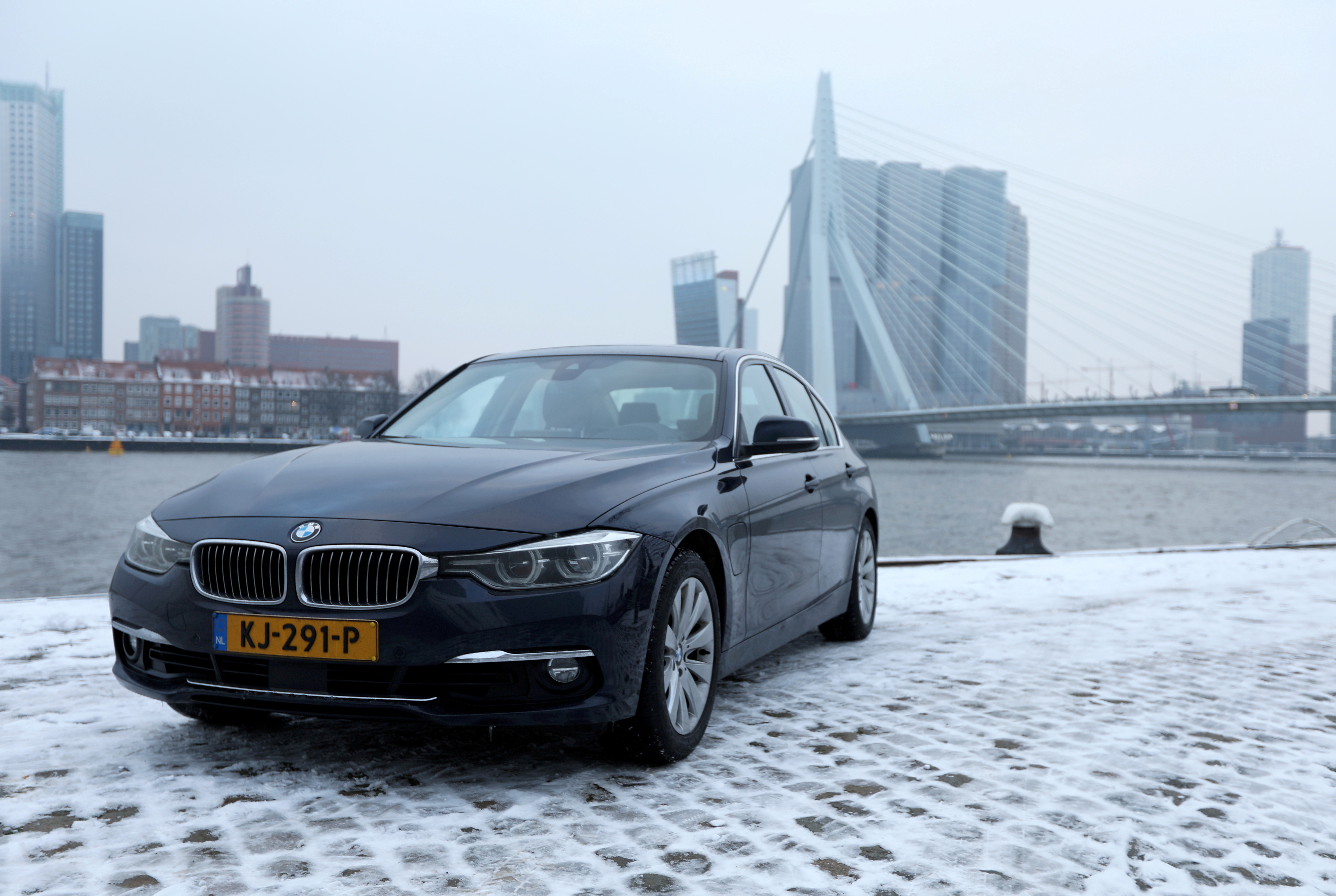 A BMW hybrid car stands near Rotterdam's Erasmus bridge