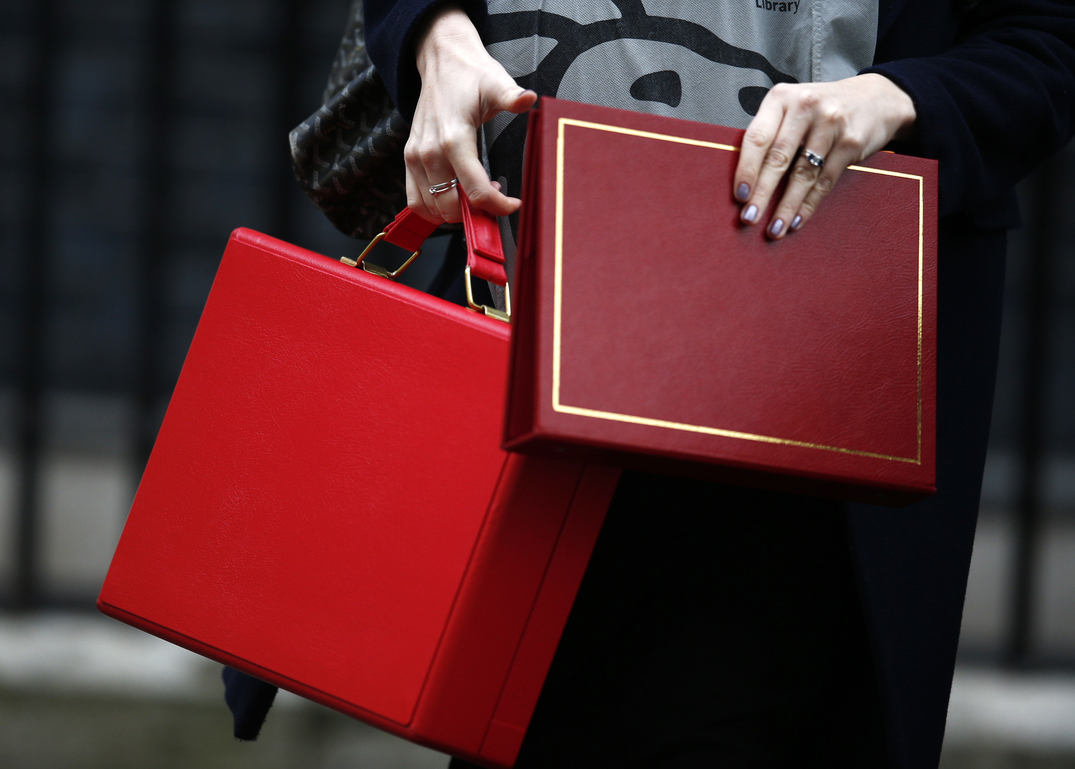 An aide carries Britain's Chancellor of the Exchequer Philip Hammond's ministerial briefcase as she and Hammond leave 11 Downing Street ahead of the Chancellor delivering his Autumn Statement in the House of Commons, in London