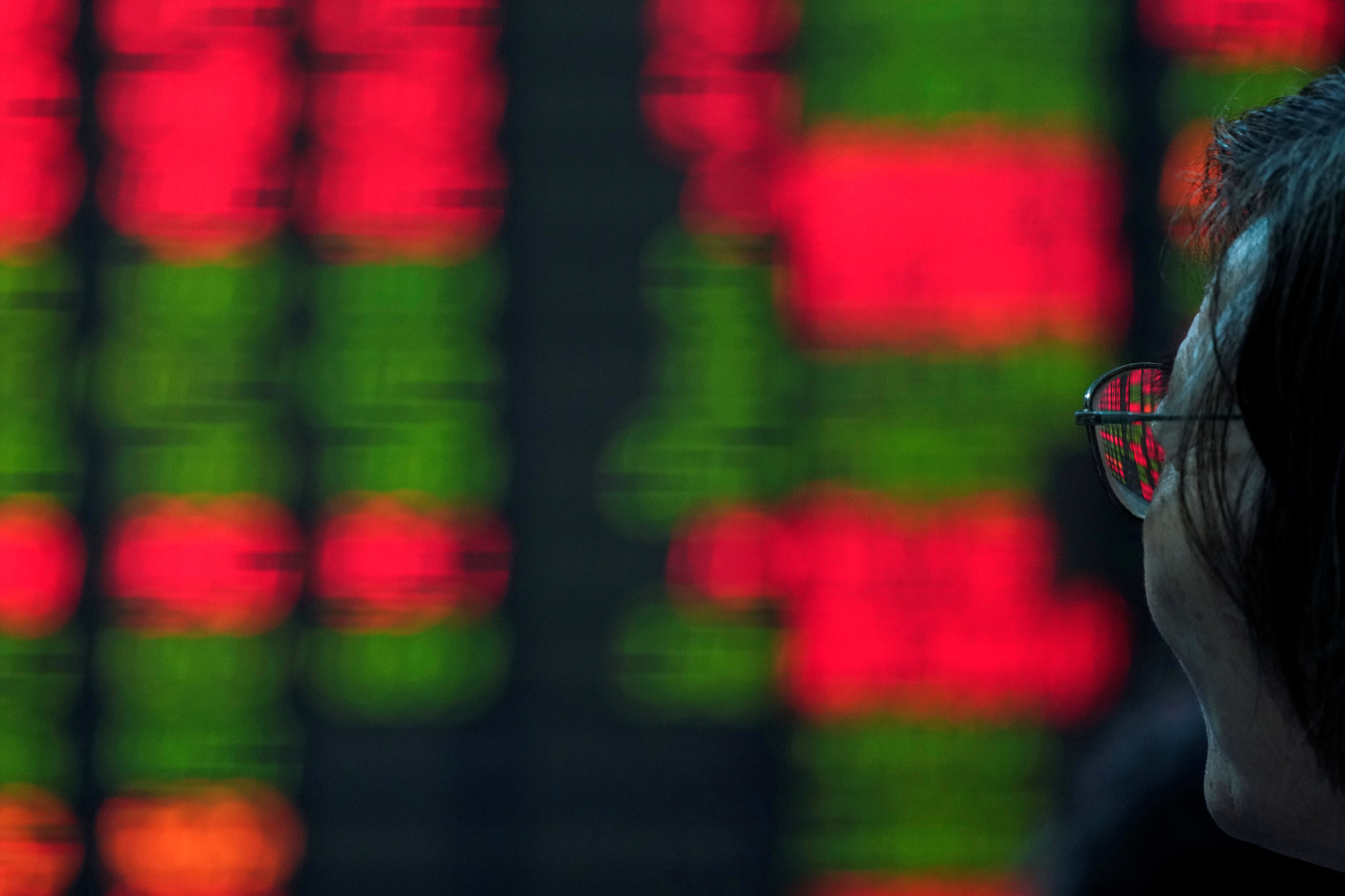 An investor looks at an electronic board showing stock information at a brokerage house in Shanghai