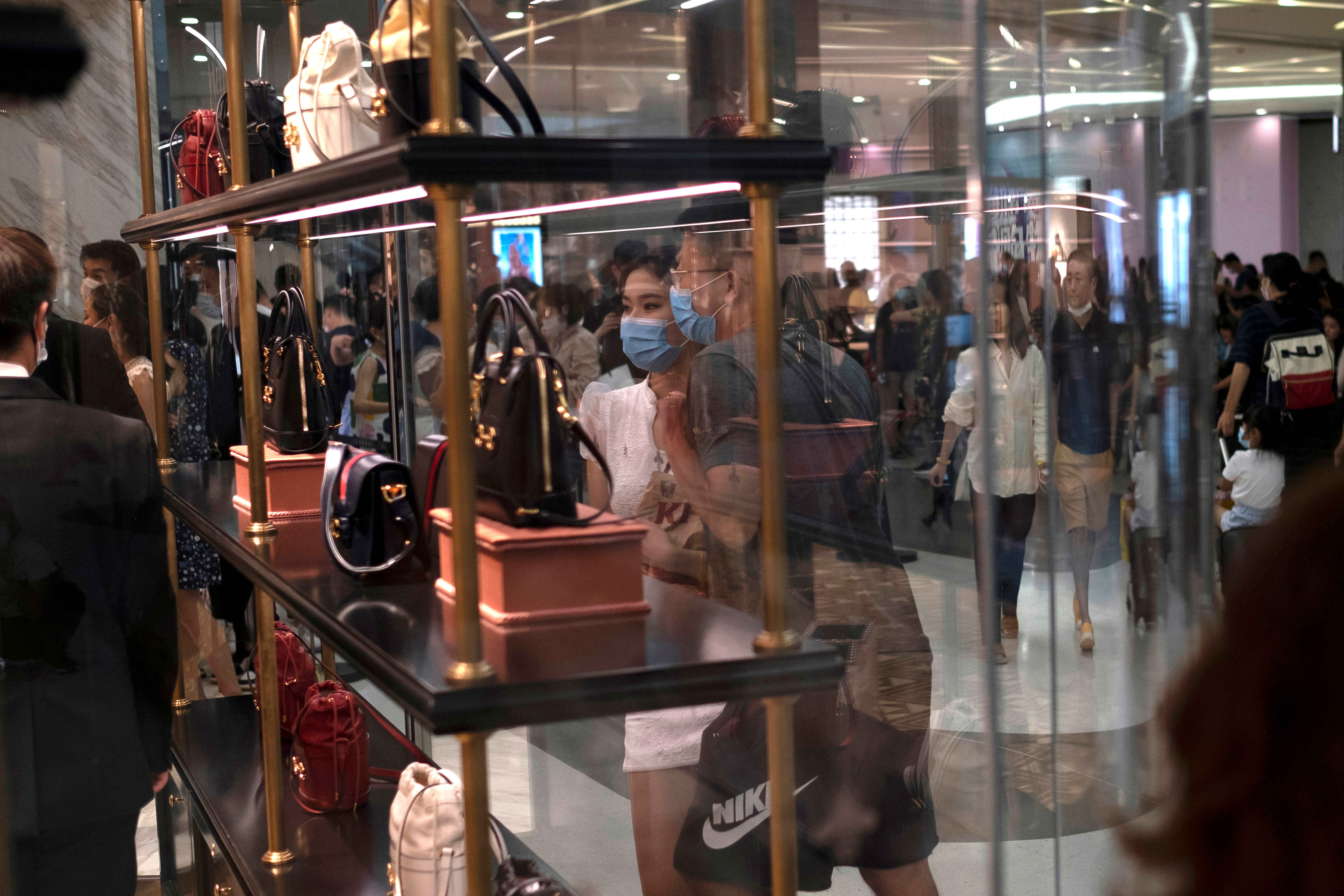 Shoppers in masks wait in line at the Louis Vuitton store in the