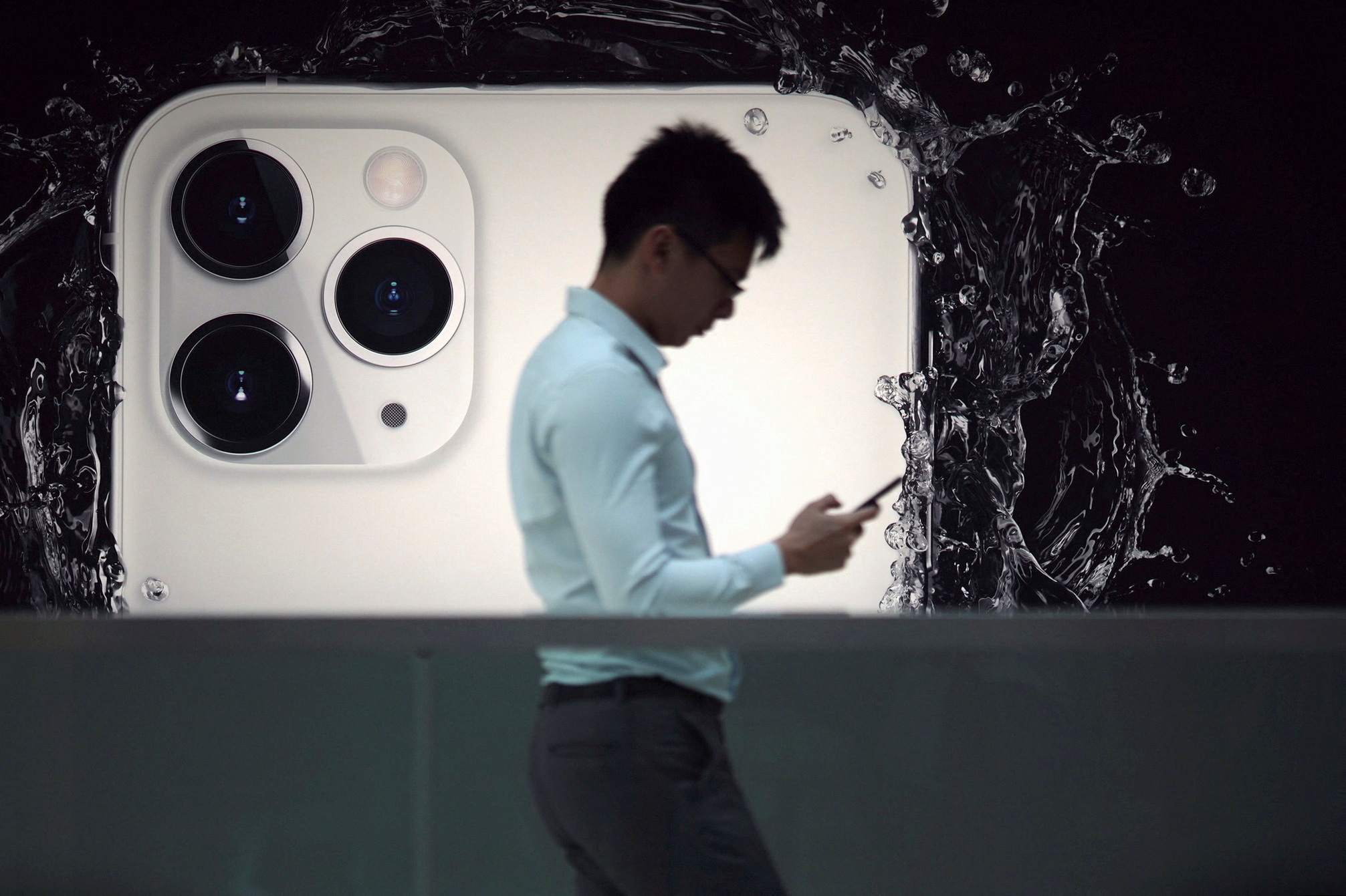 A man walks next to an advertisement for Apple's new iPhone 11 Pro at the Apple Store in IFC, Central district, Hong Kong, China