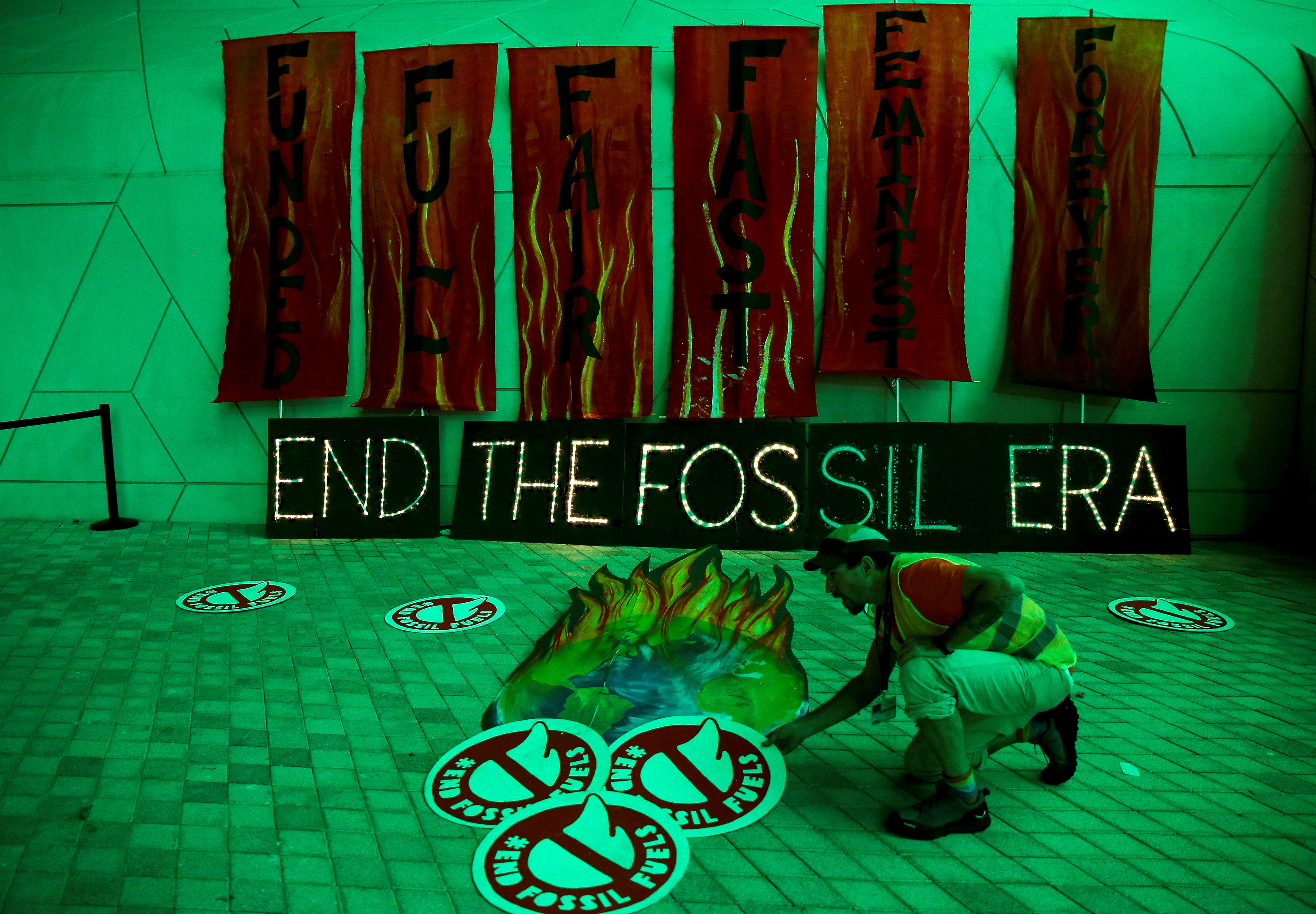 A climate activist arranges artwork against fossil fuels at Dubai's Expo City during the United Nations Climate Change Conference COP28 in Dubai