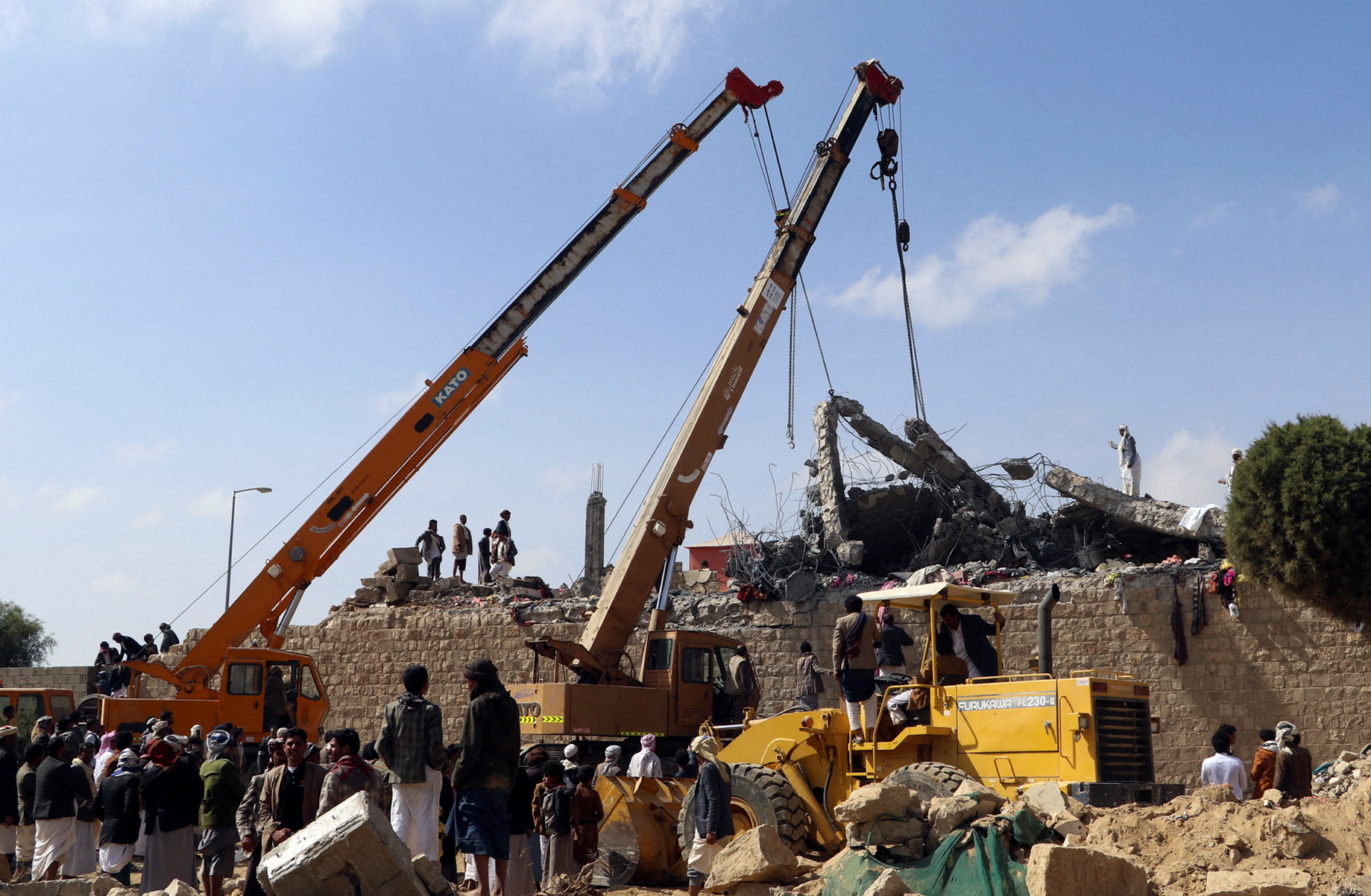 Rescuers use cranes to remove collapsed concrete roof of a detention center hit by air strikes in Saada