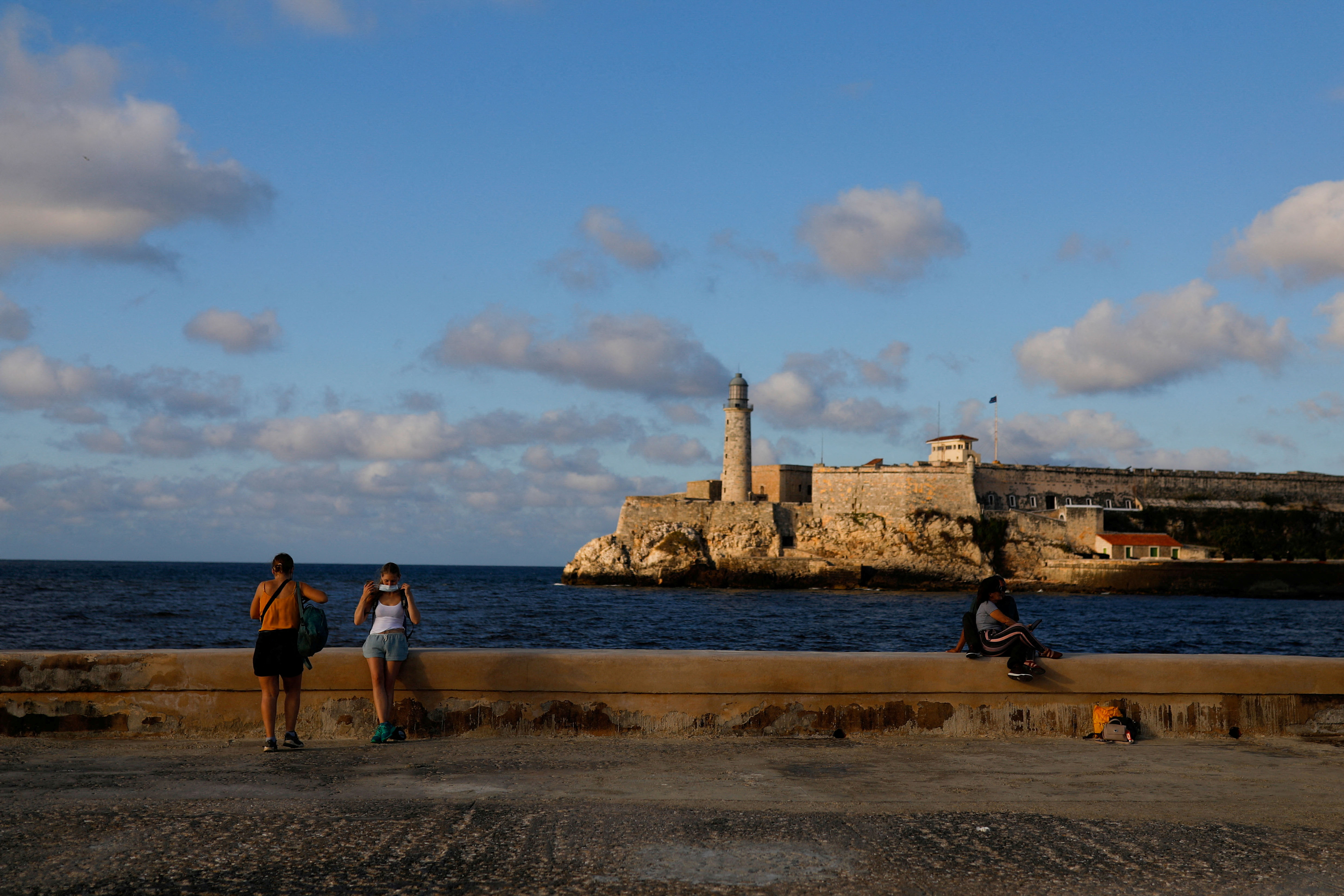 A tourist puts on a face mask after posing for a picture at the seafront El Malecon in Havana